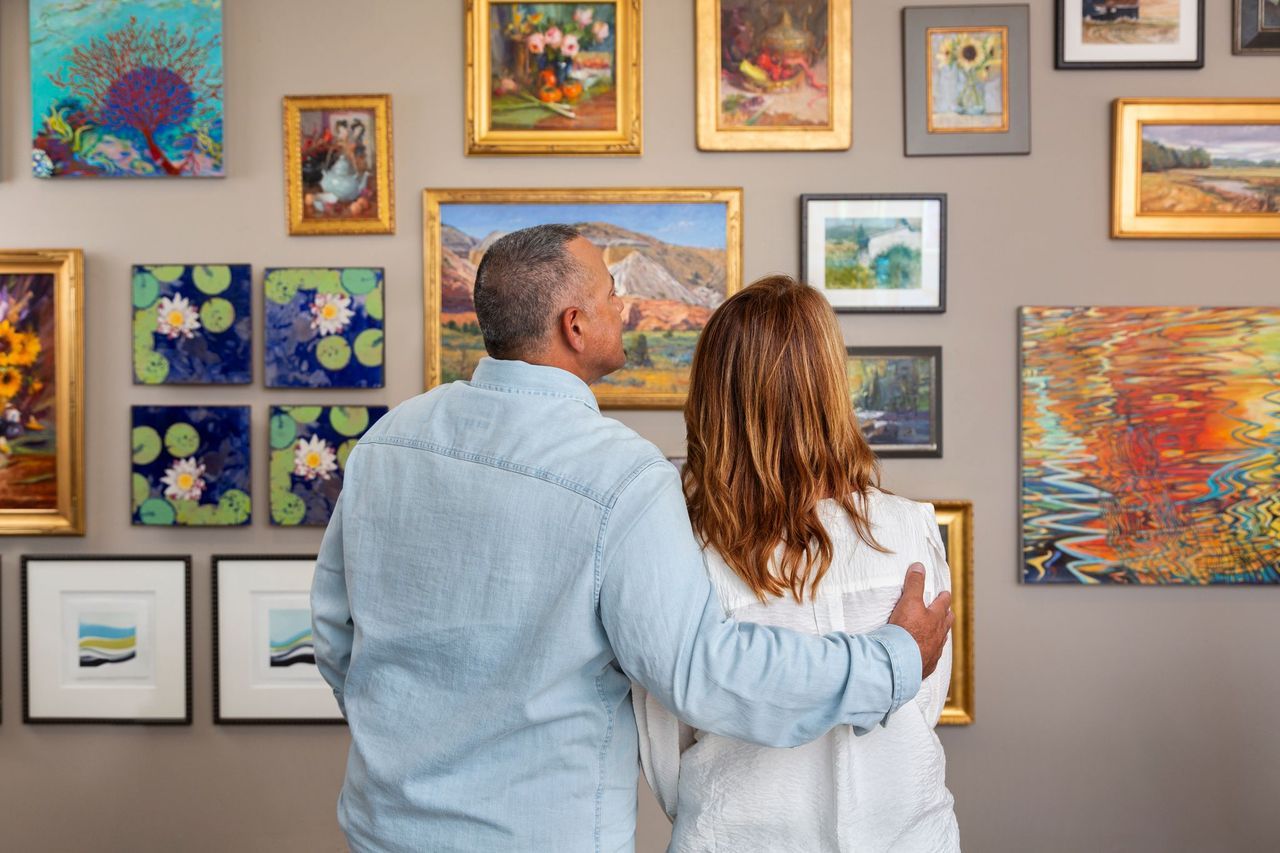Two people admiring paintings at an art gallery