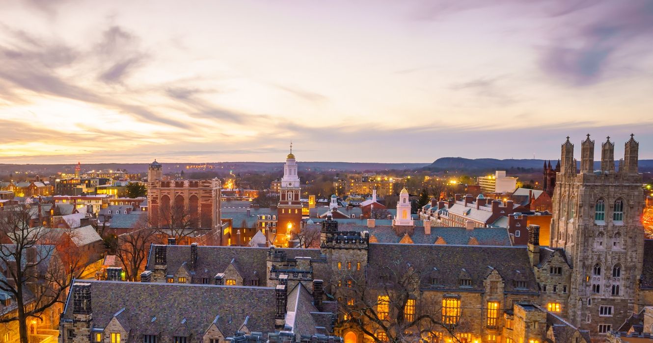 https://static1.thetravelimages.com/wordpress/wp-content/uploads/2023/03/aerial-view-of-historic-buildings-and-yale-campus-in-new-haven-ct-at-dusk.jpg