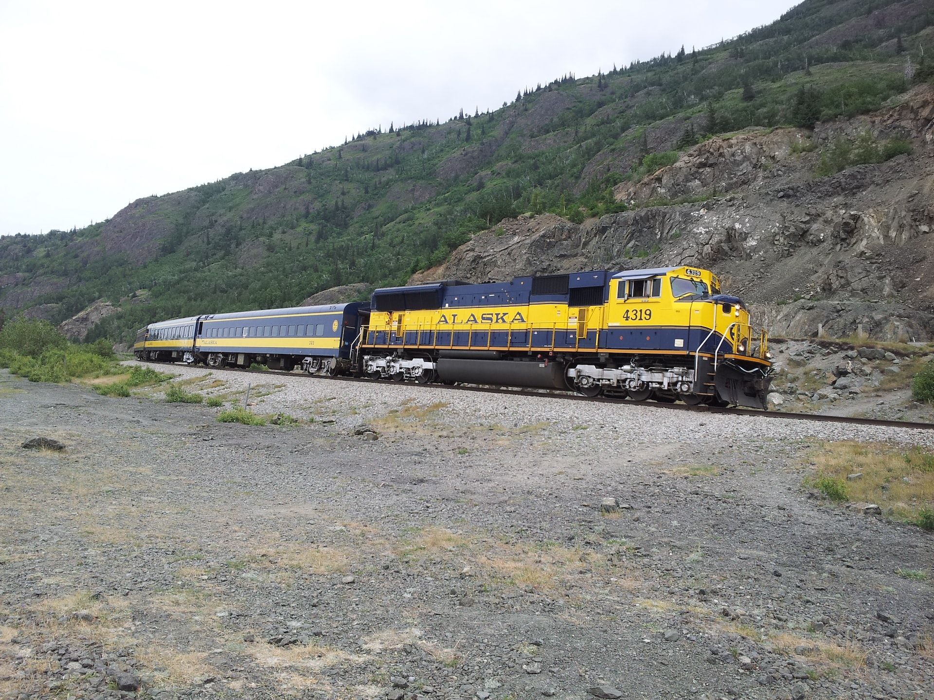 An Alaskan train zips through Anchorage near the Chugach mountain range.