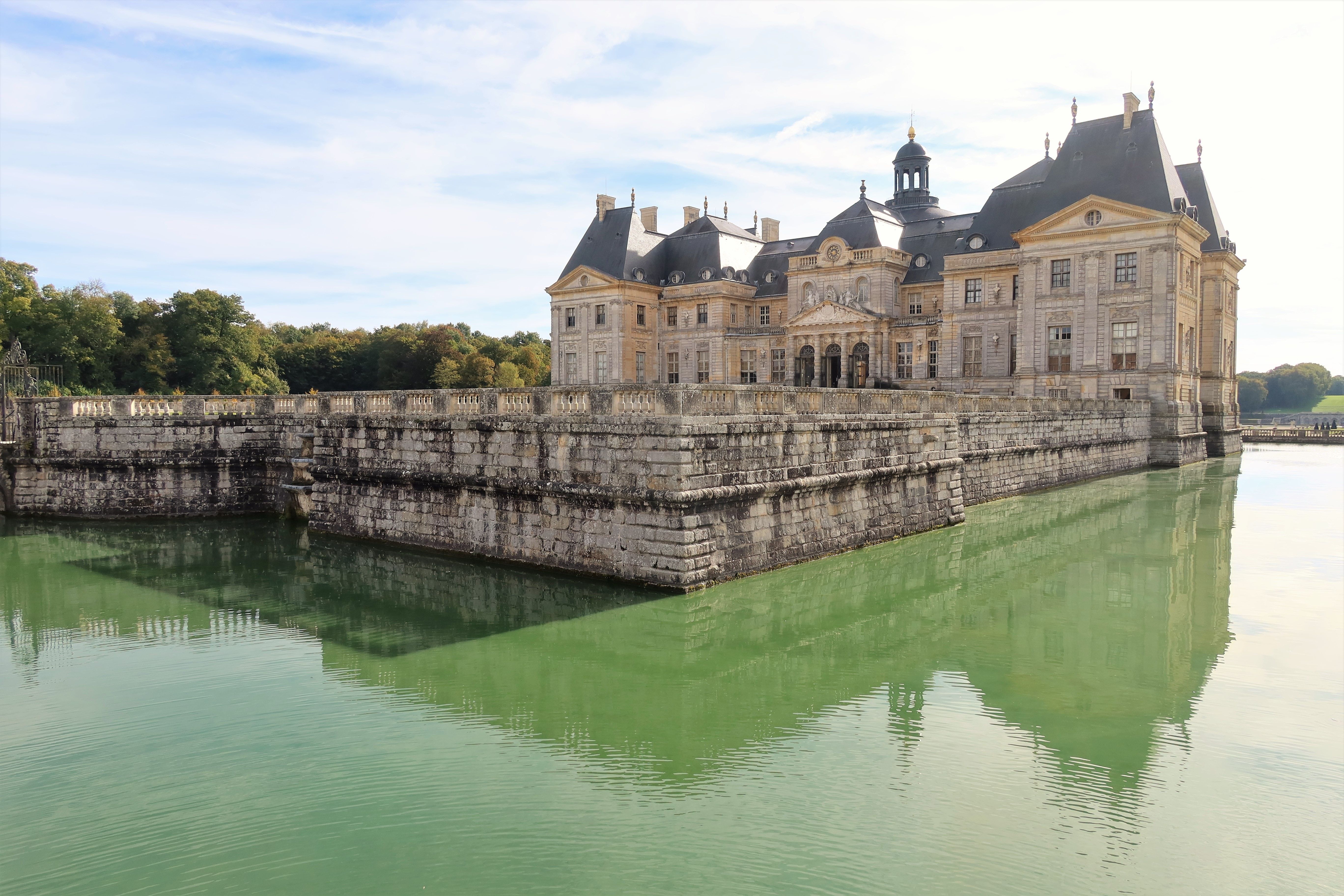 Château de Vaux-le-Vicomte visto da água, durante o dia.  Foto de Chris Linnett no Unsplash.