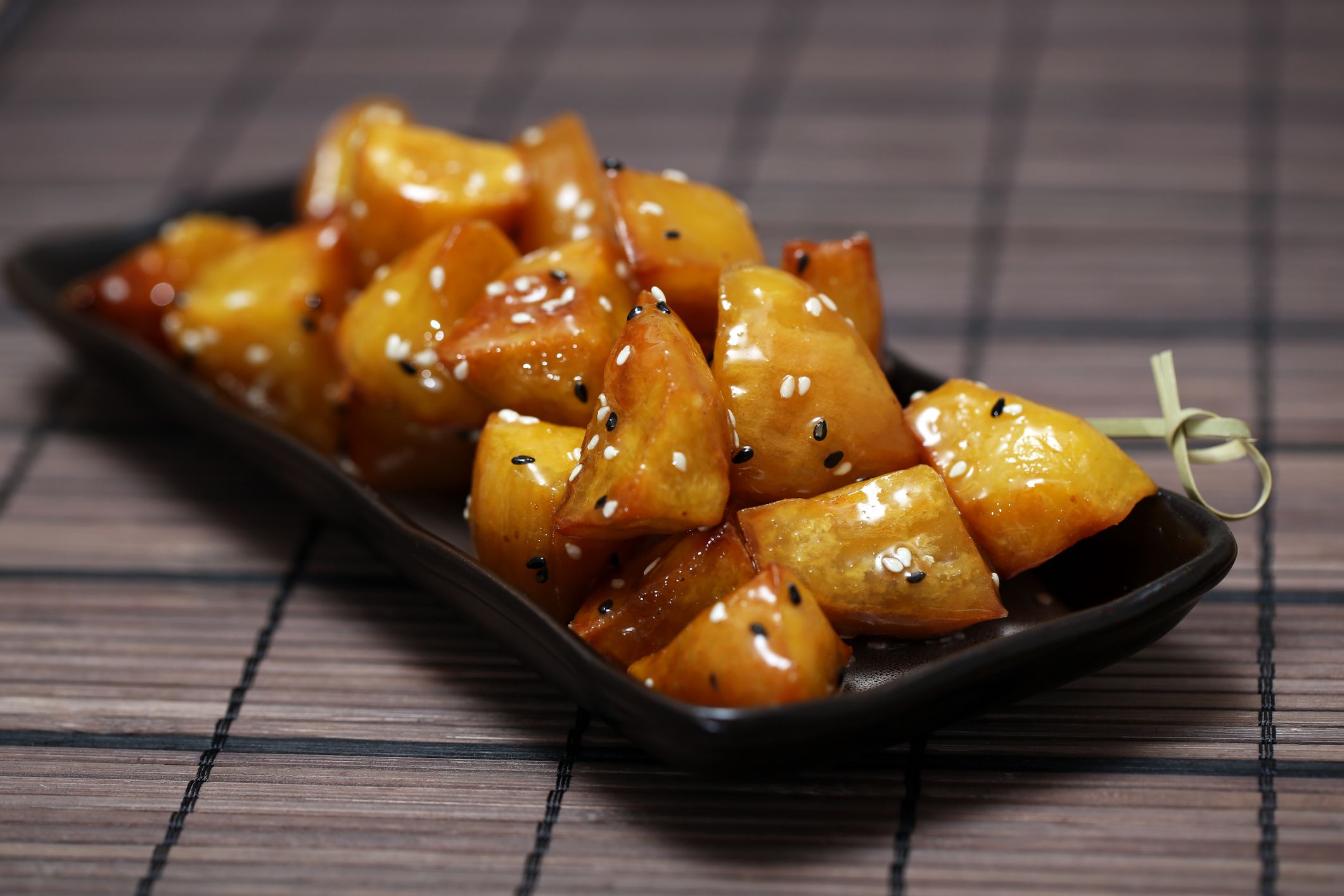 Candied Sweet Potato, Daigaku Imo, traditional Japanese food deep fried sweet potato coated with sweet syrup on the black plate