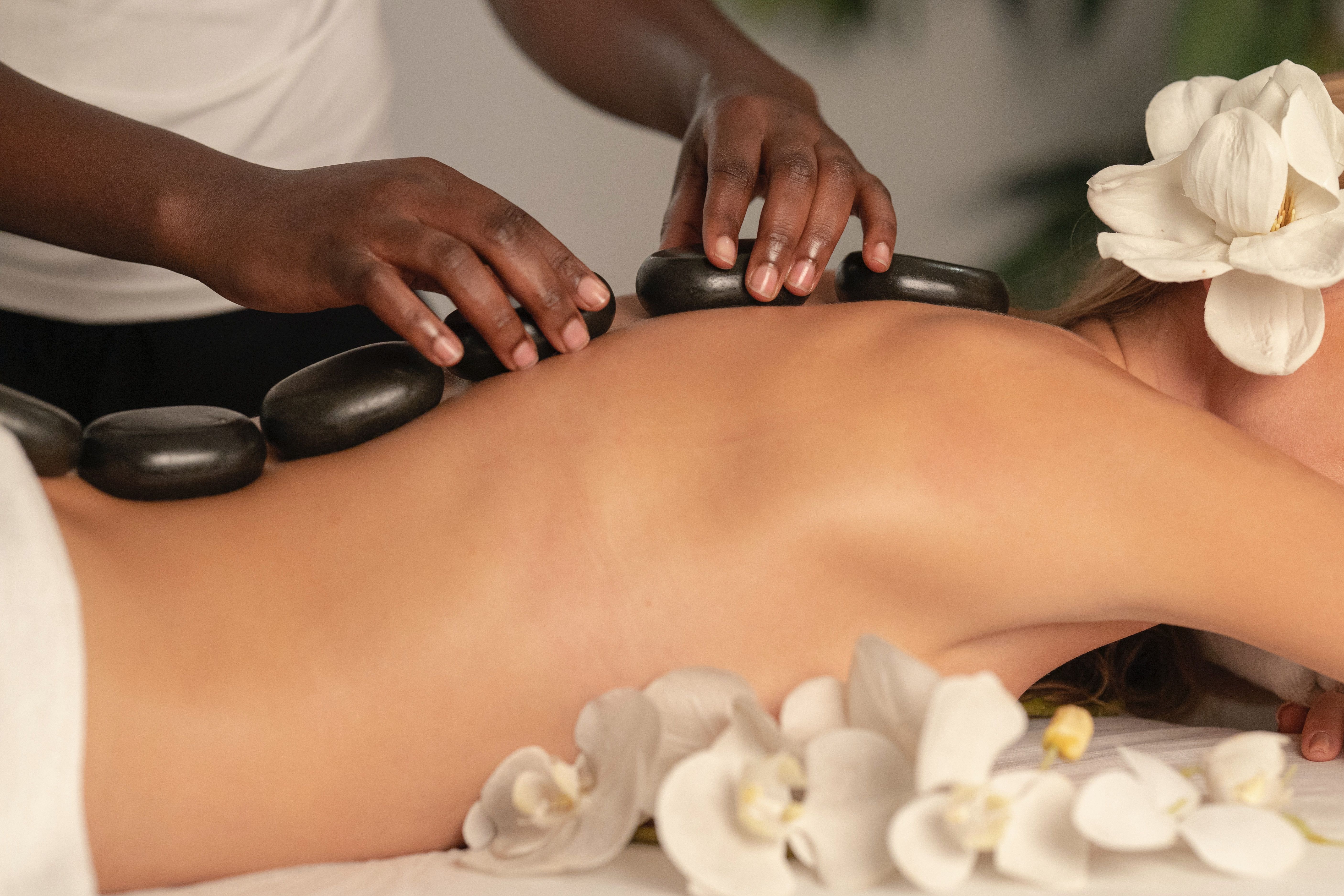 Applying stones to a woman's back for spa treatment 