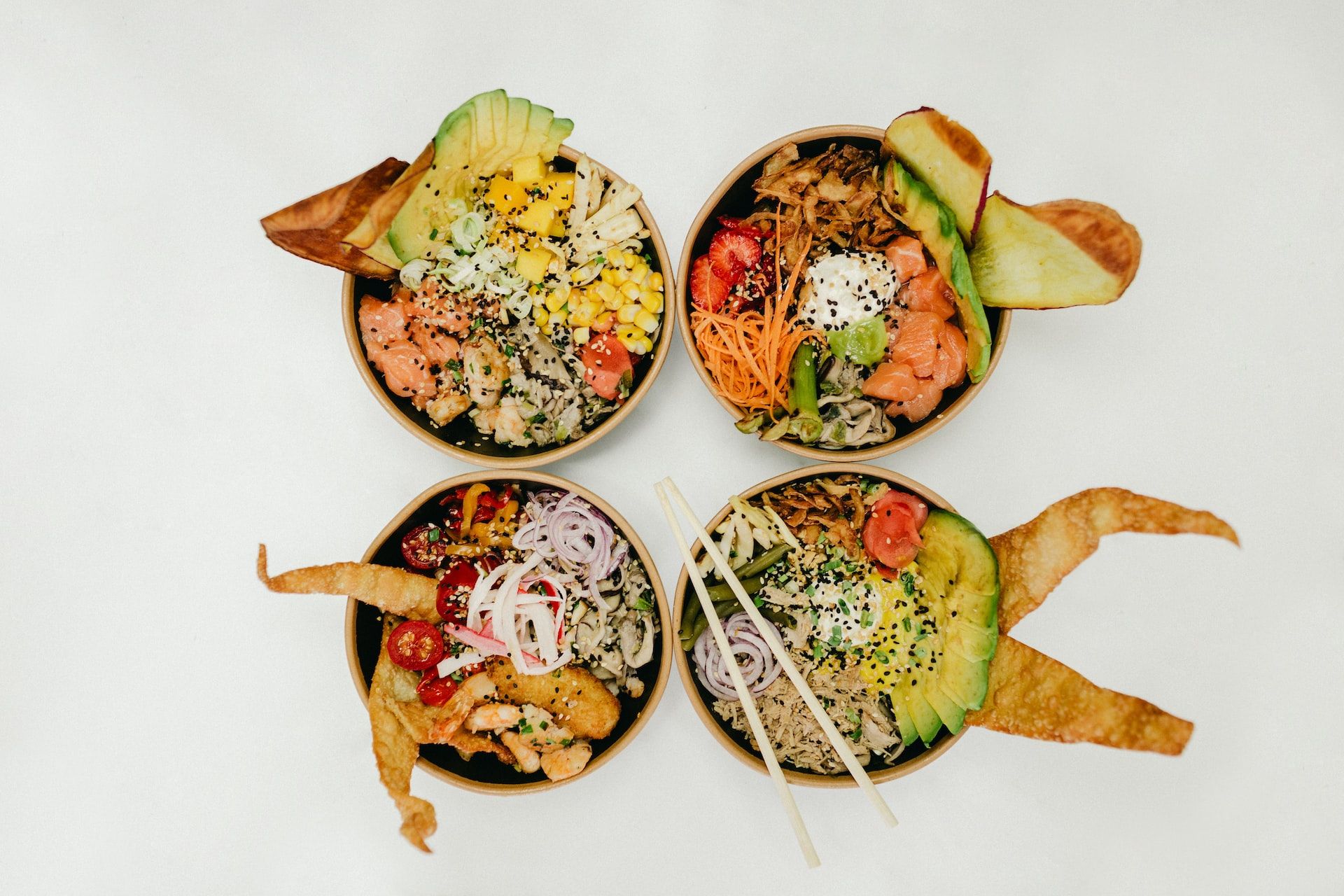 Imagem de quatro poke bowls coloridos com peixe e legumes 