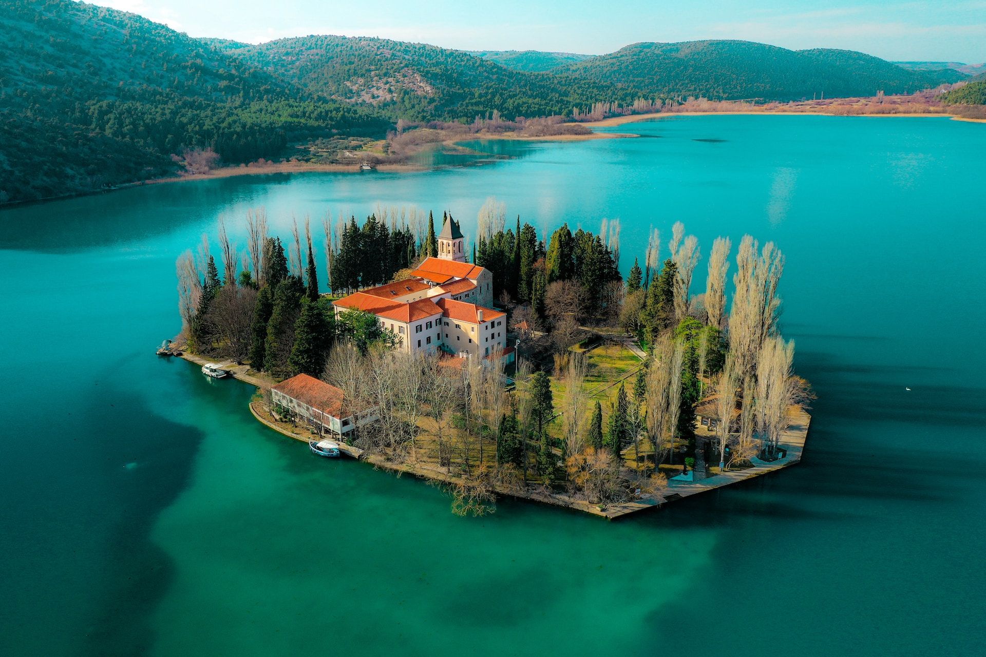 Island with a church in the middle of a lake surrounded by mountains