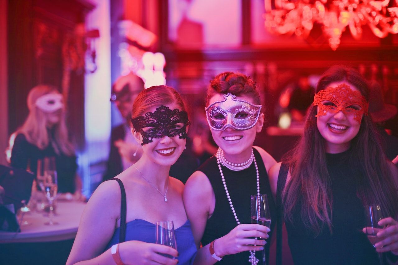 Mulheres usando máscaras segurando suas bebidas em um clube