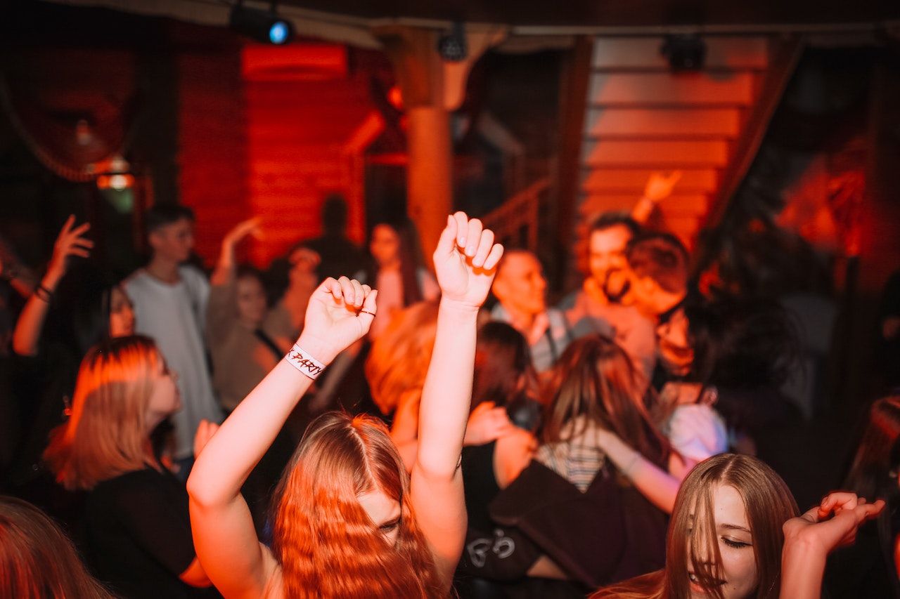 Pessoas levantando as mãos e dançando em um clube