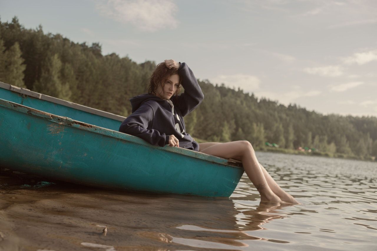 Uma mulher de preto sentada casualmente em uma canoa em um rio