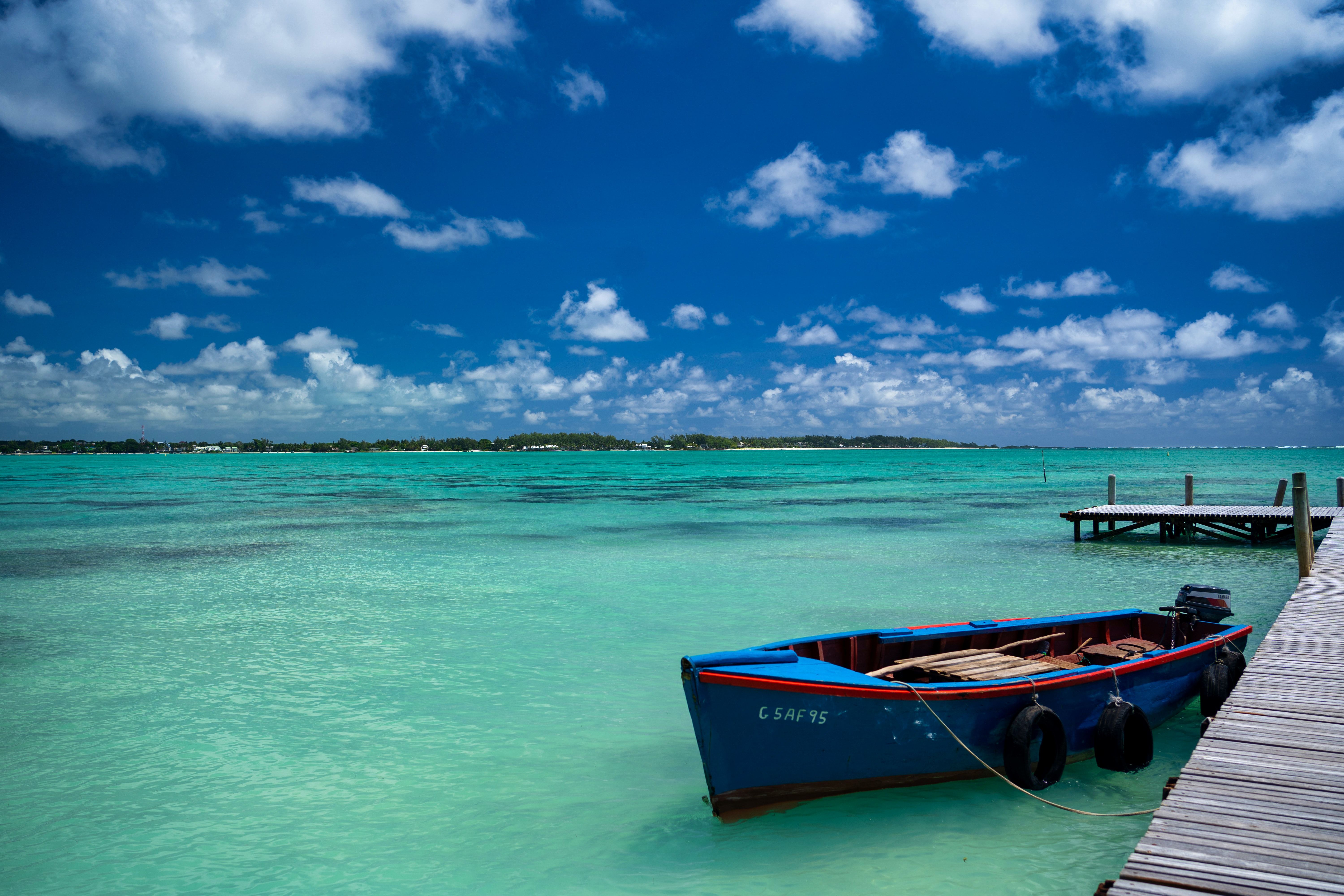 A boat by a wooden dock in the blue ocean in Mauritius