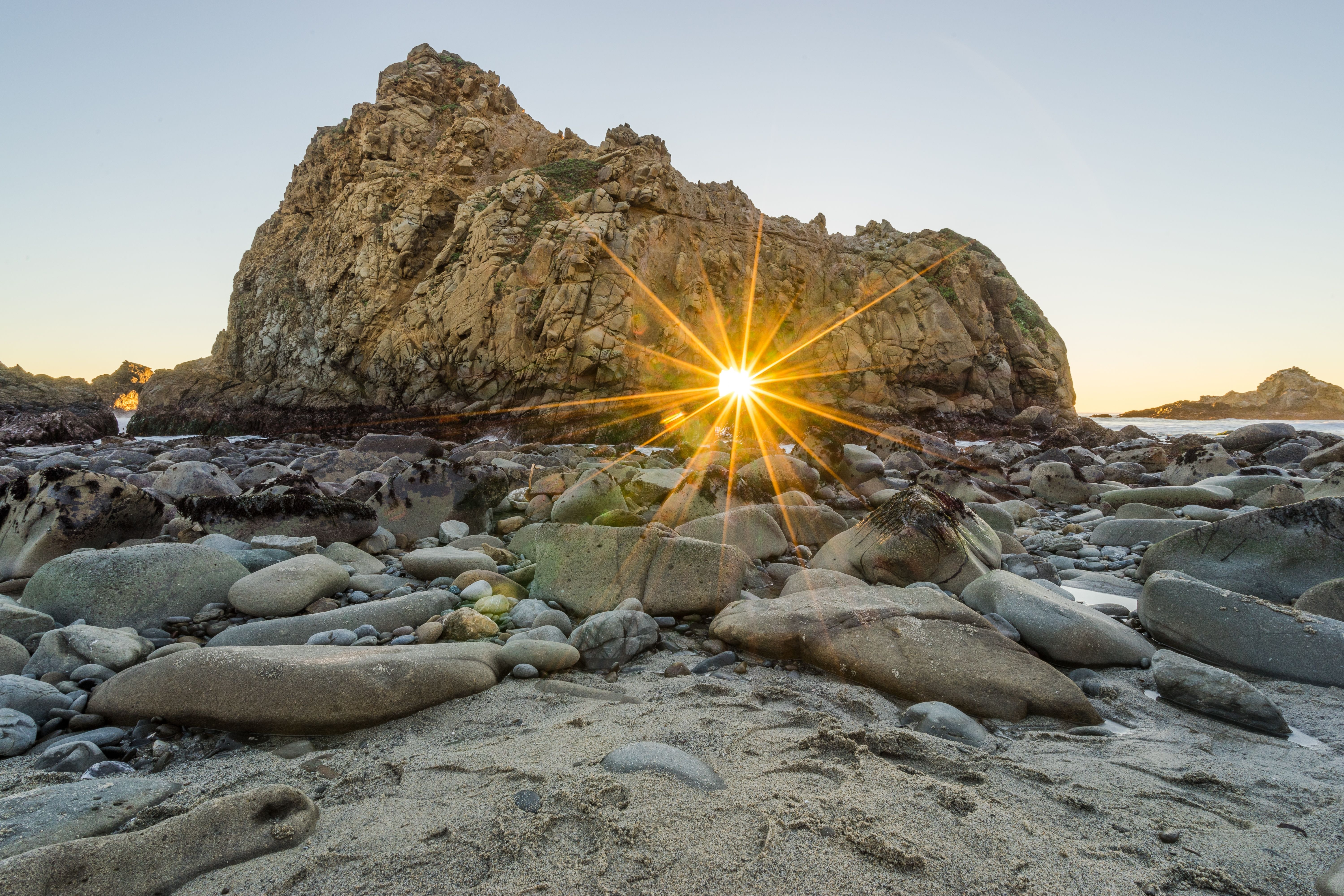 O sol se põe em um nível perfeito atrás do arco Keyhole em Pfeiffer Beach, Califórnia