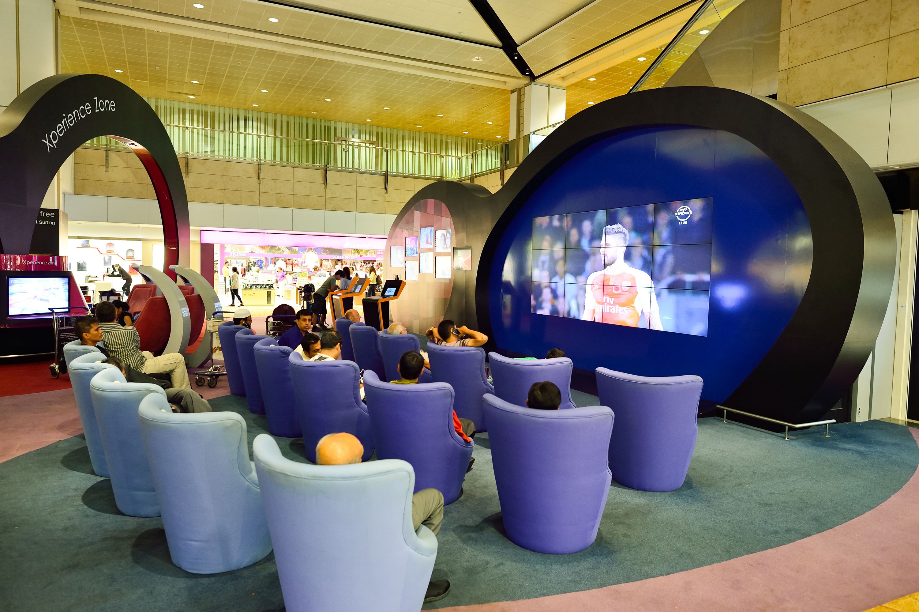 Cadeiras em frente a uma grande tela de TV no aeroporto de Cingapura 