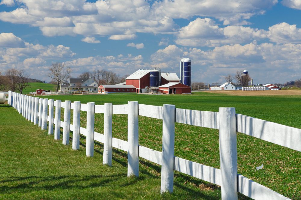 White fence with Amish farm in the distance in Lancaster, PA