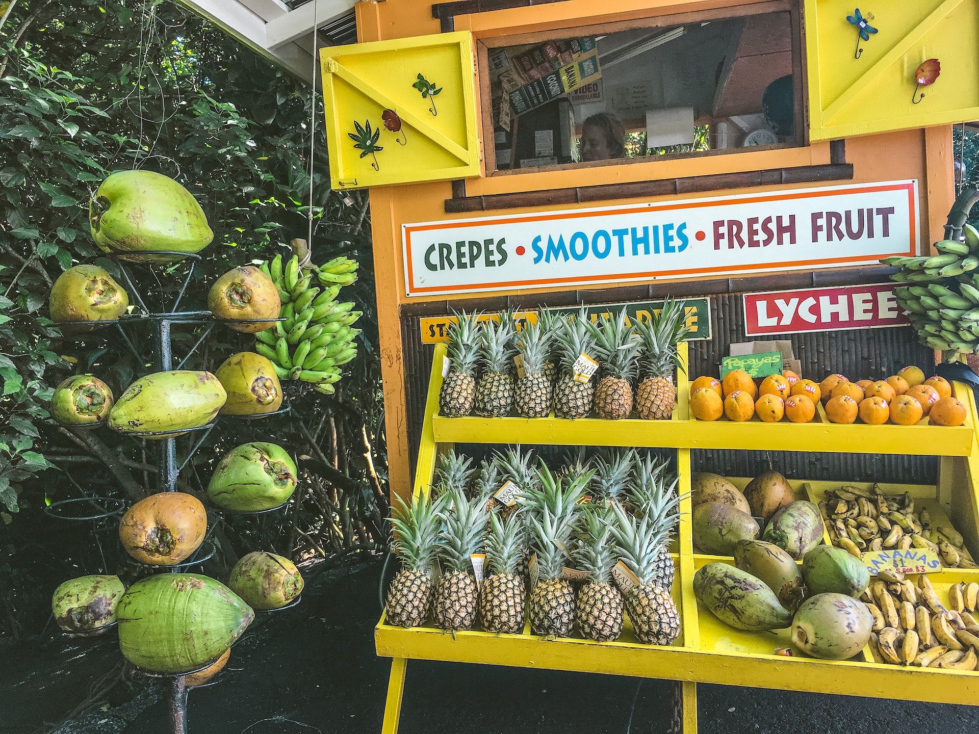 Uma barraca de comida em uma das paradas gastronômicas da Hana Highway, com cocos frescos, crepes, smoothies e frutas