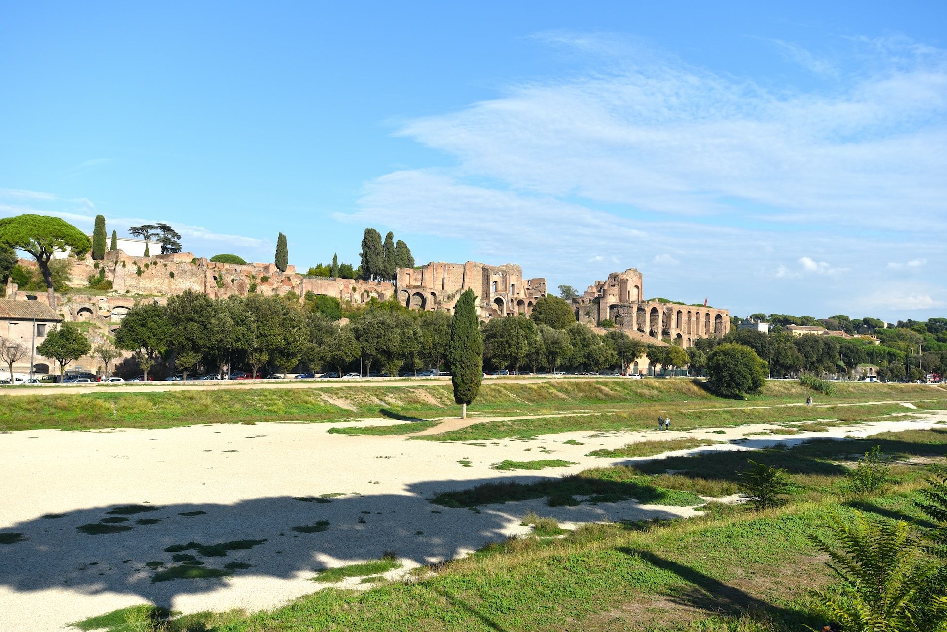 Side view of the Roman Circus Maximus with green trees and a bright blue sky above