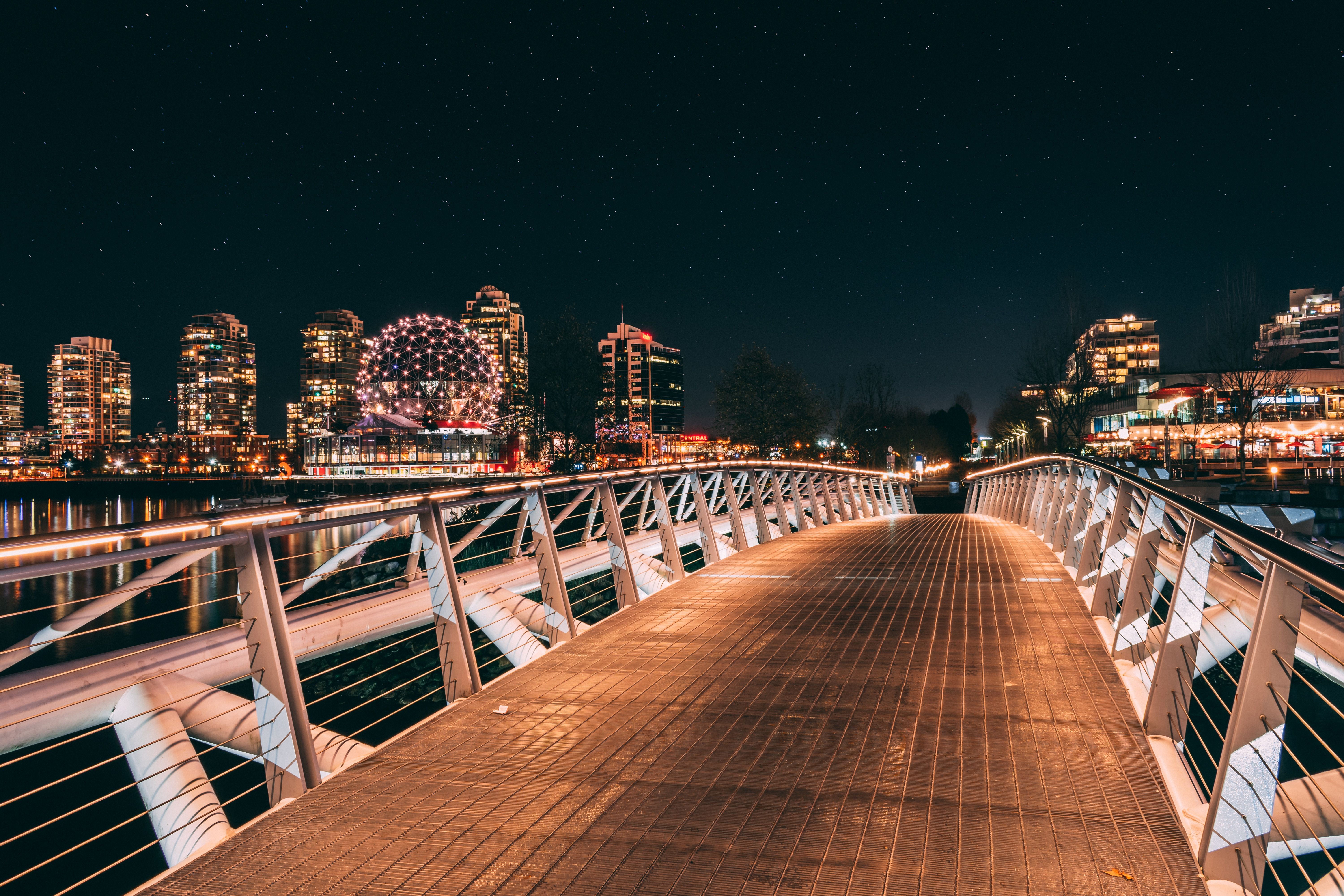 Bridge at night with white railings and city lights 