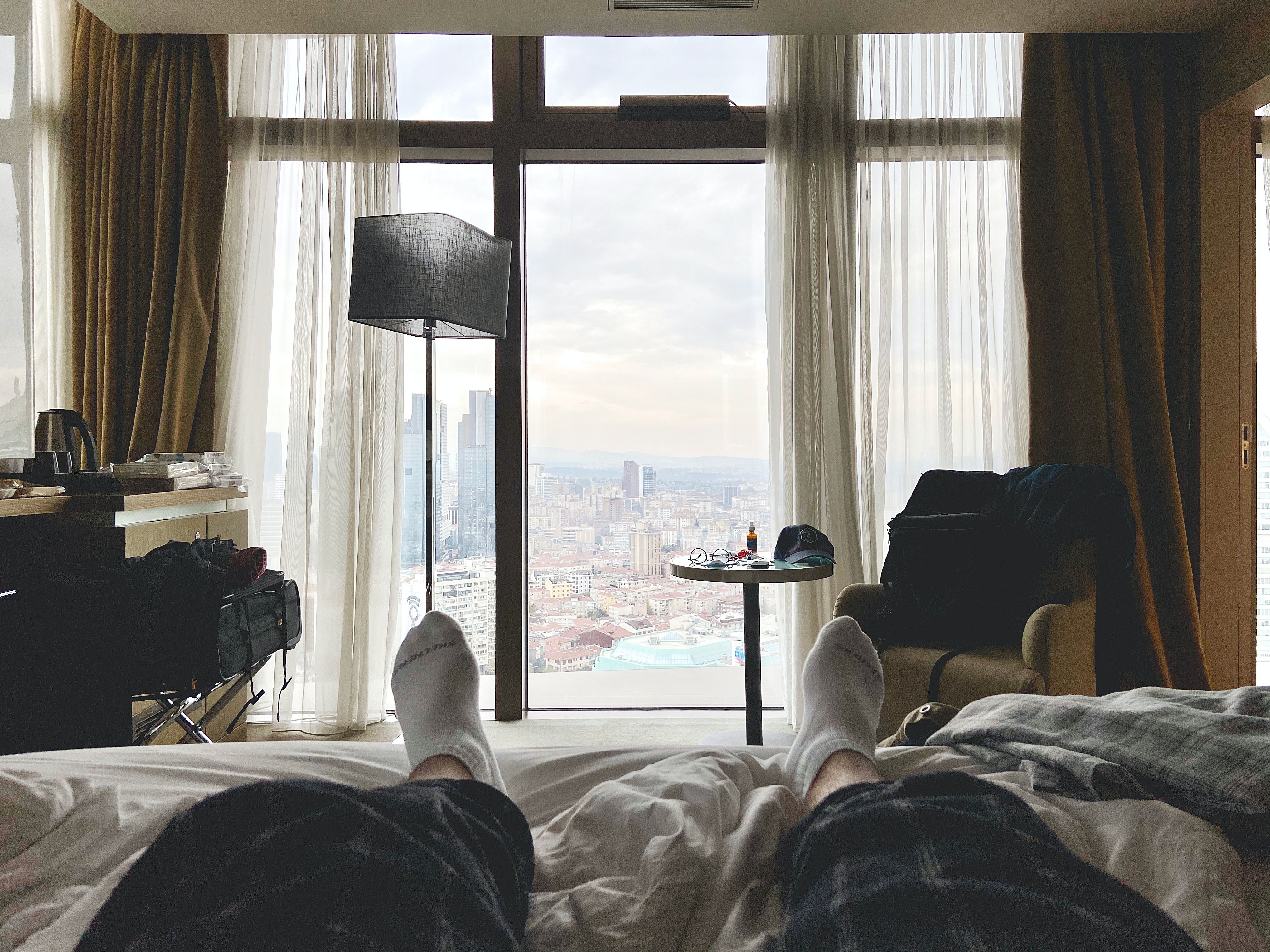 homem na cama em um quarto de hotel com vista para Istambul como pano de fundo