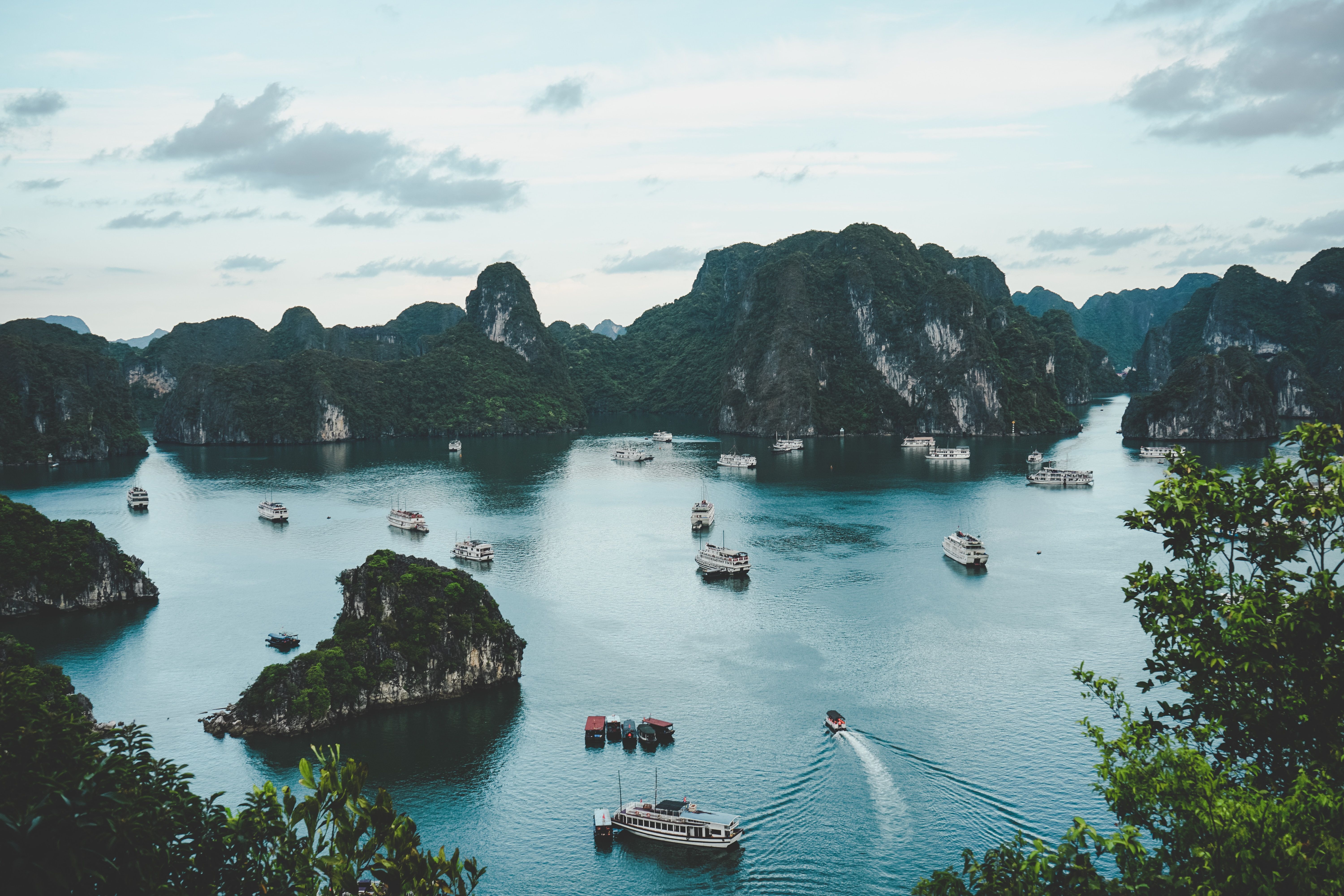 Boats sailing on water near a hill in Ha Long 