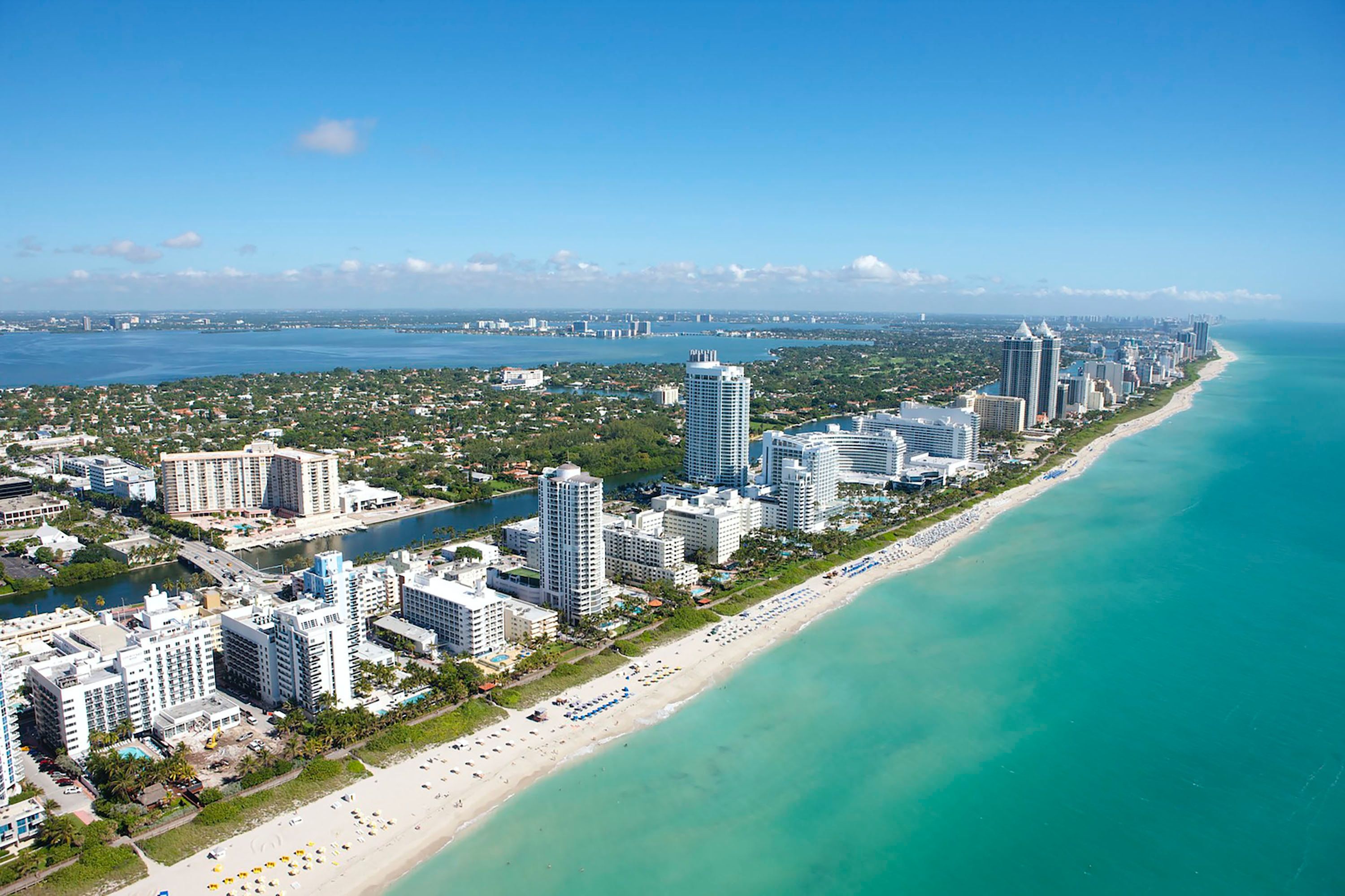 Blue waters and white sand beach with tall buildings on shore 