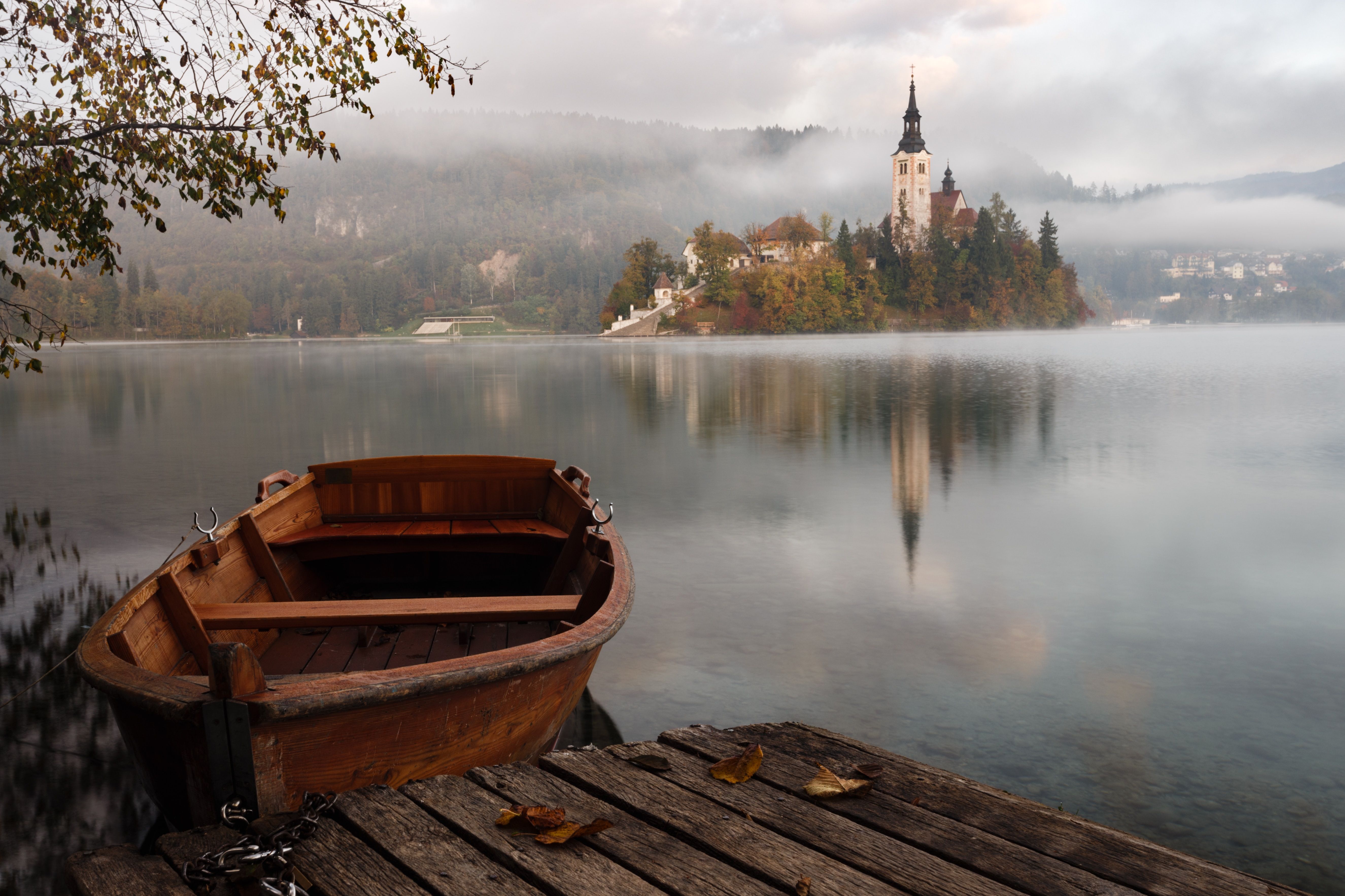 Barco a remo de madeira em primeiro plano e o Lago Bled ao fundo 