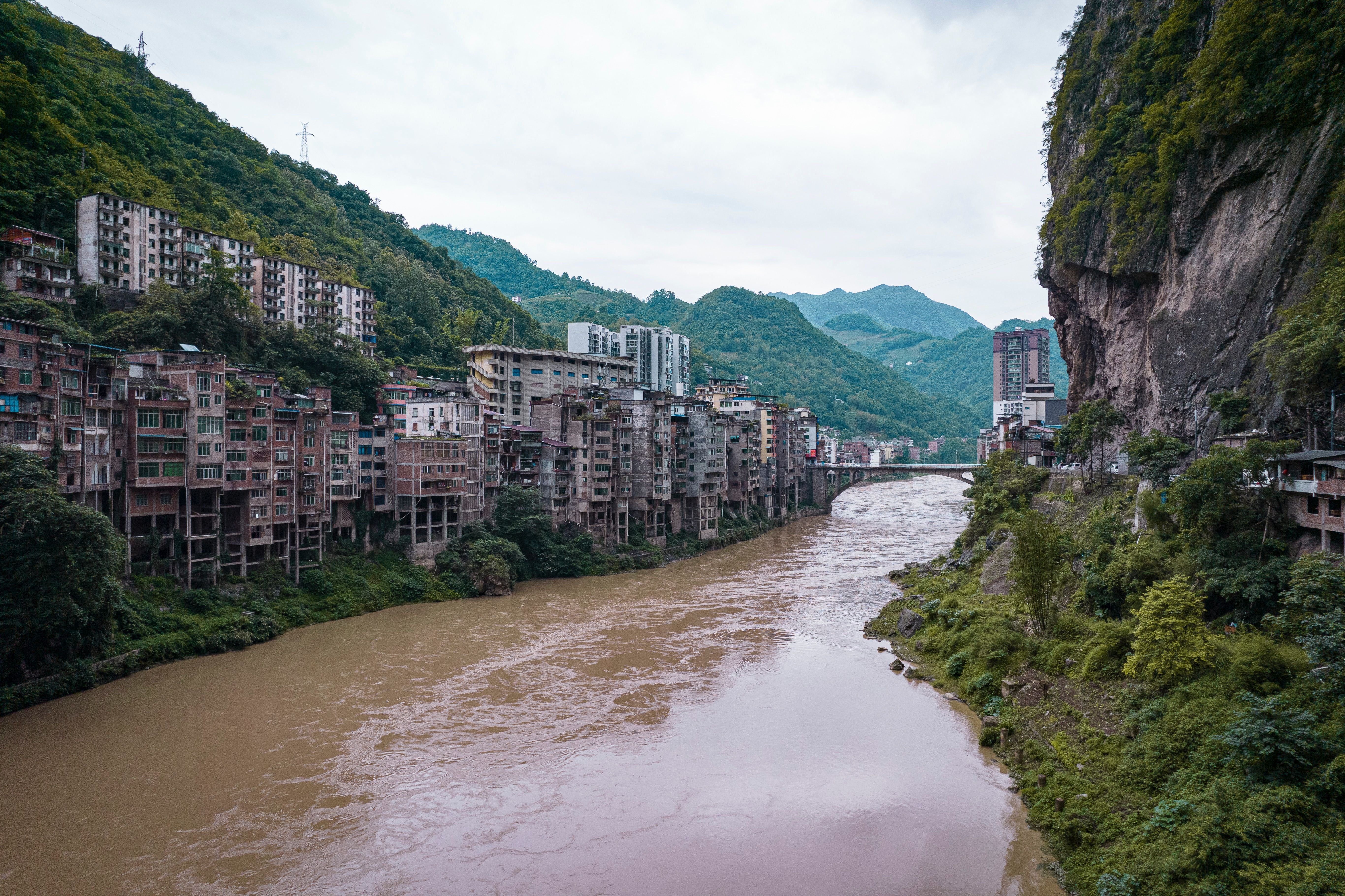 O rio Yunnan com edifícios e rochas cobertas de plantas nas laterais