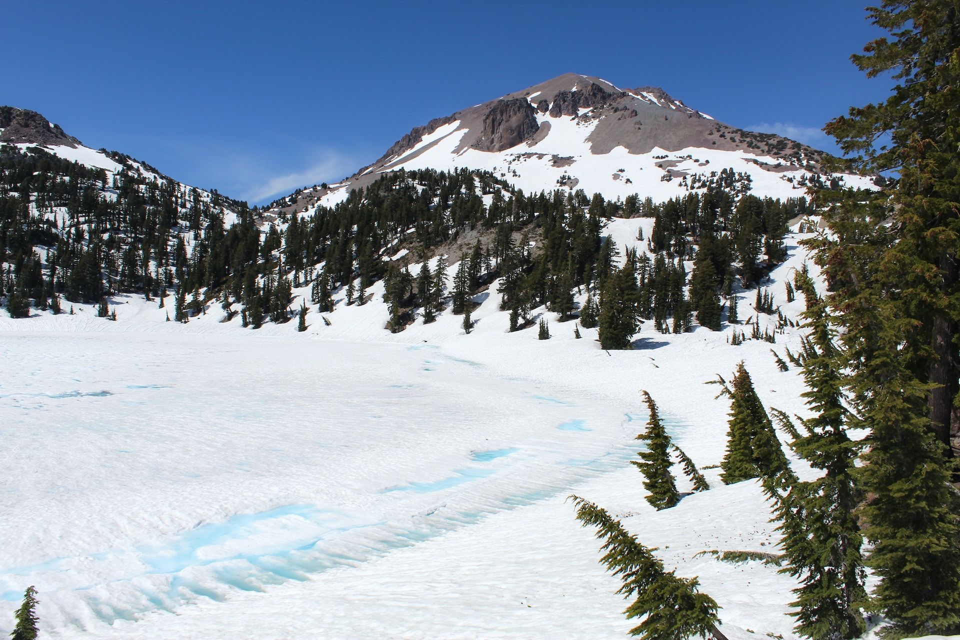 Snowy trail surrounded by trees with Lassen Peak visible in the background
