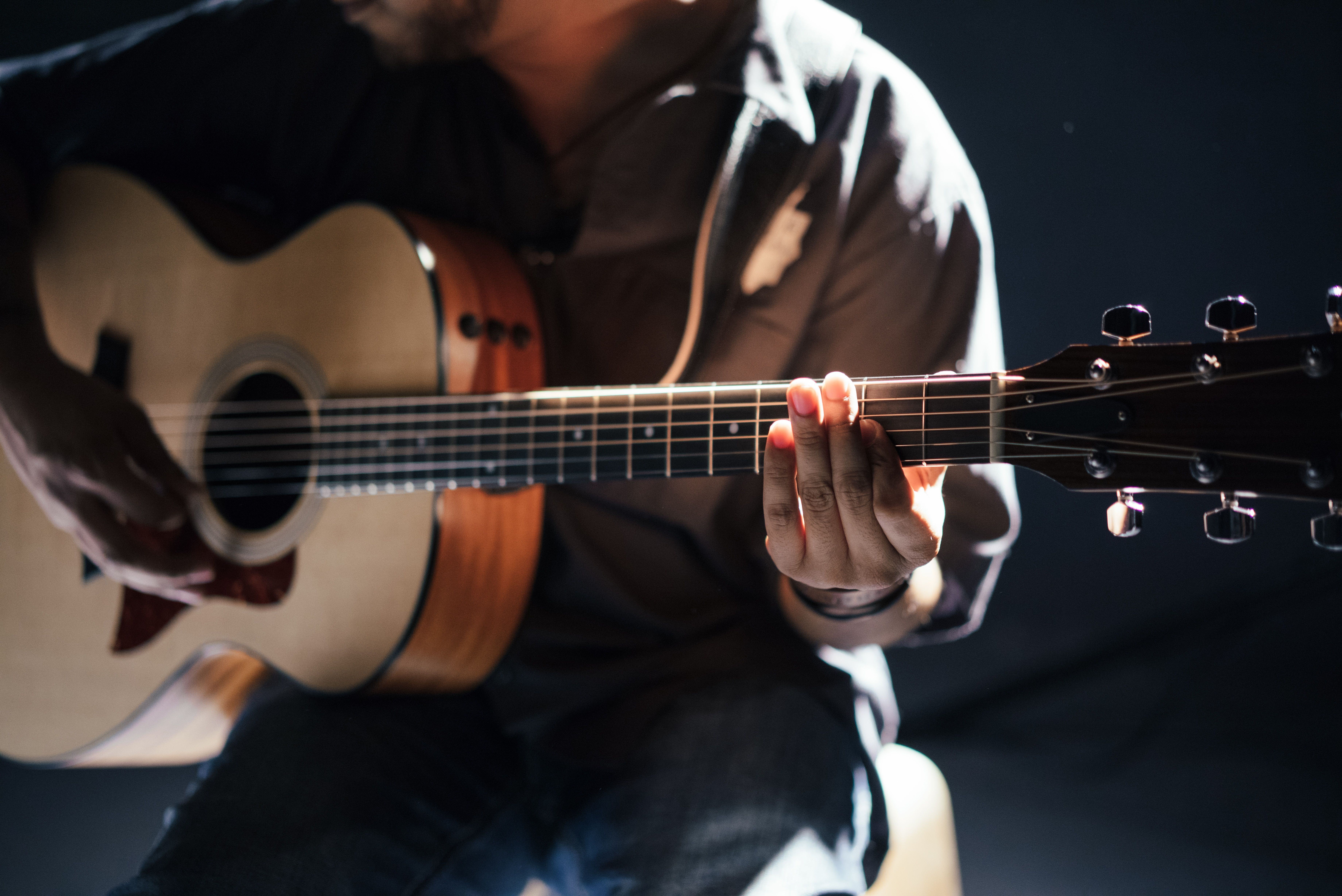 Hands on strings of an acoustic guitar 