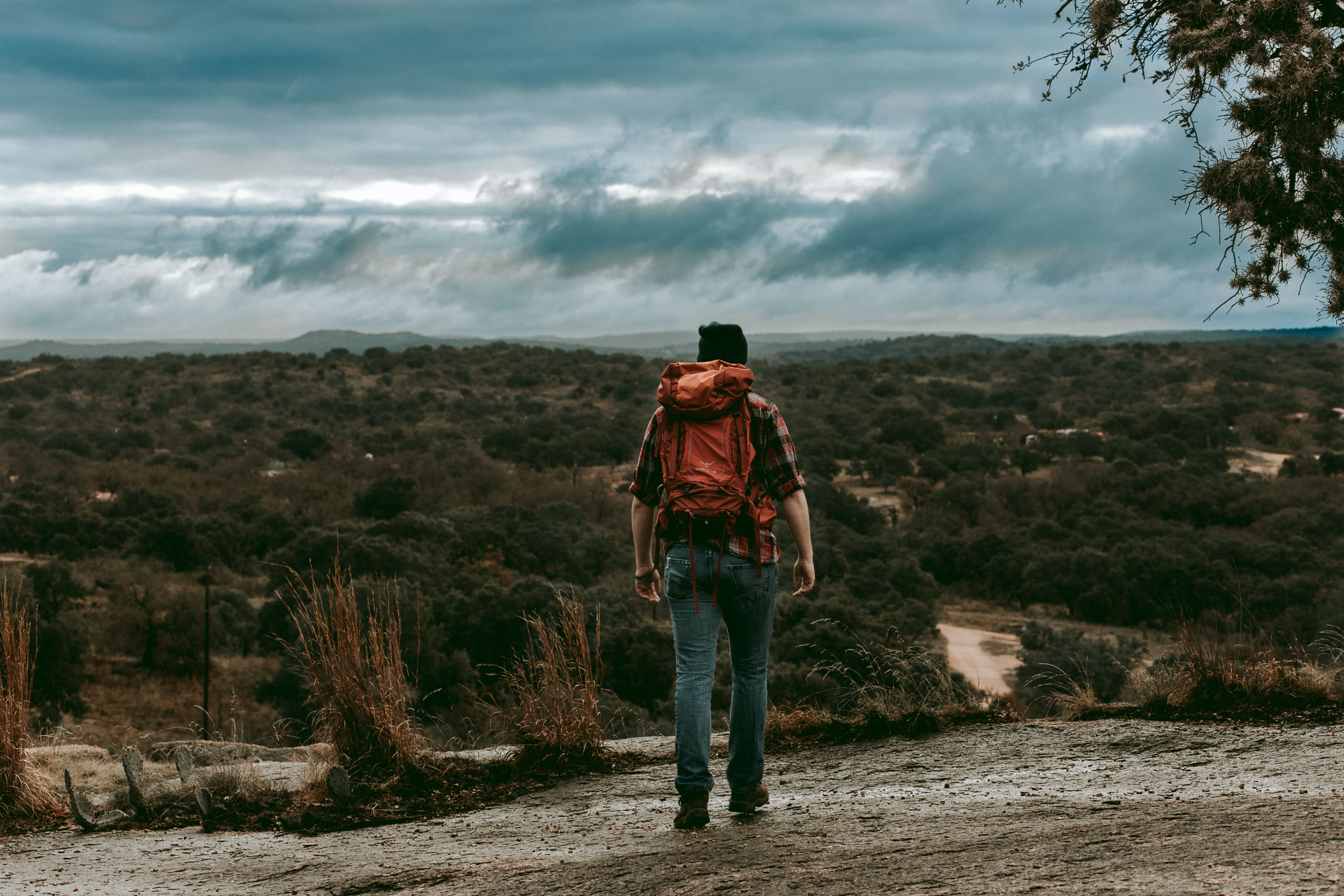 Pessoa em uma jaqueta marrom caminhando na área natural do estado de Enchanted Rock