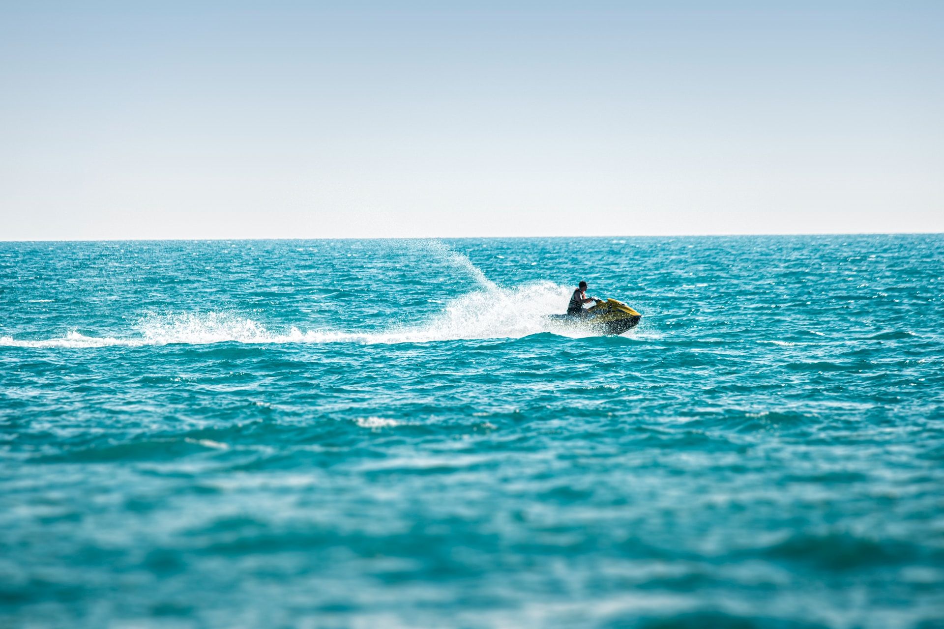 Jet skier taking to the waves on clear blue water 