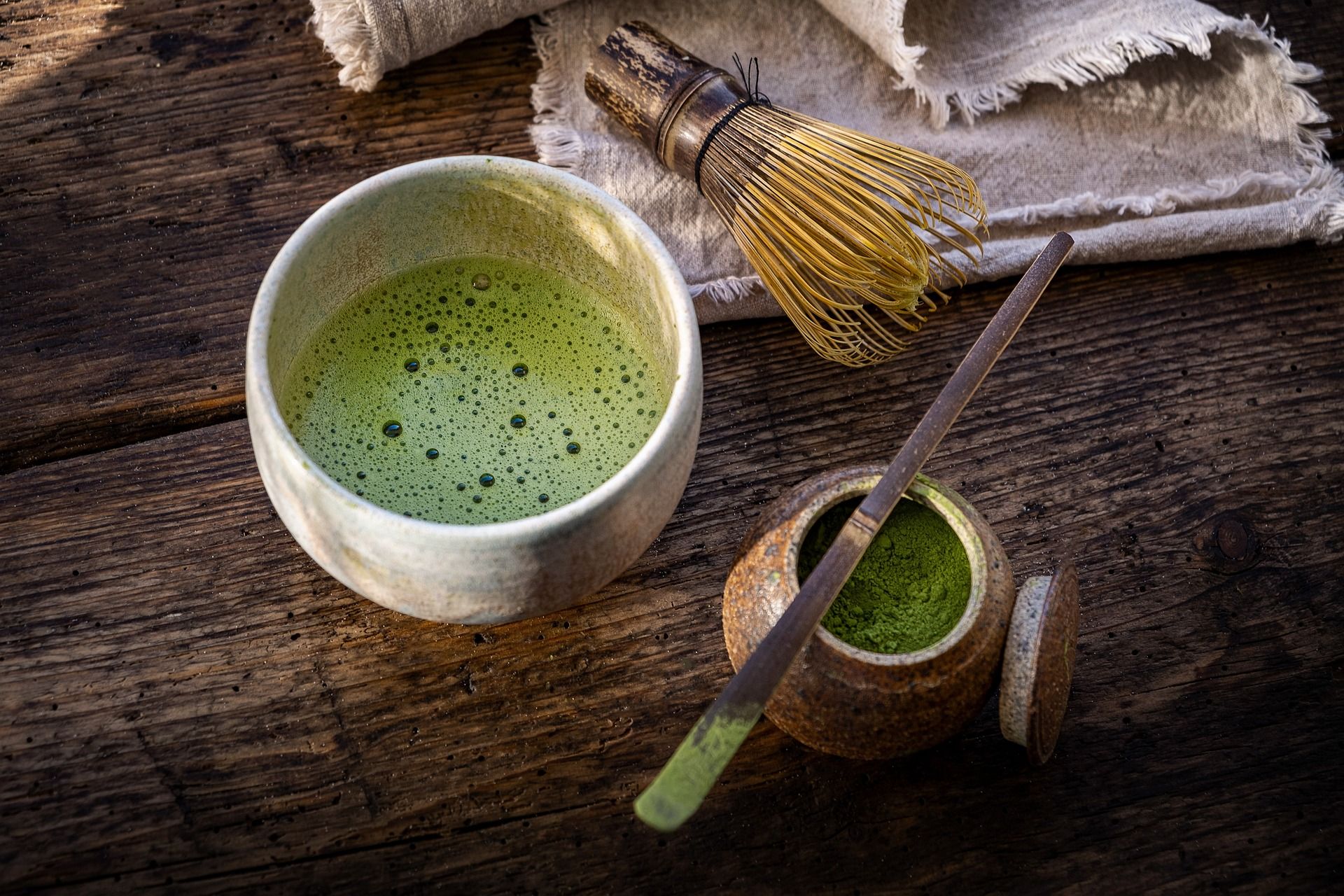 A bowl of matcha tea with a whisk