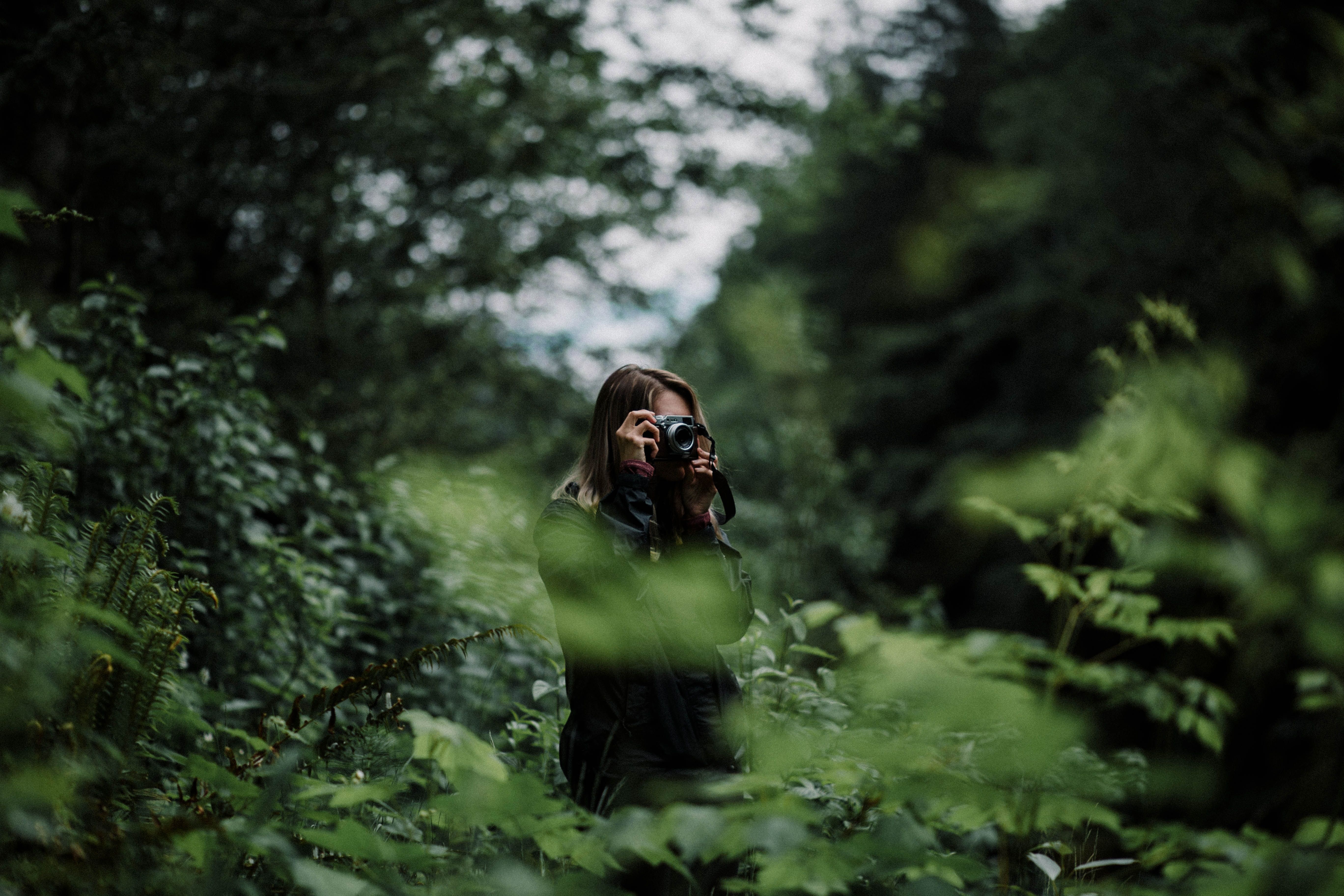Woman on a forest trail with a camera 