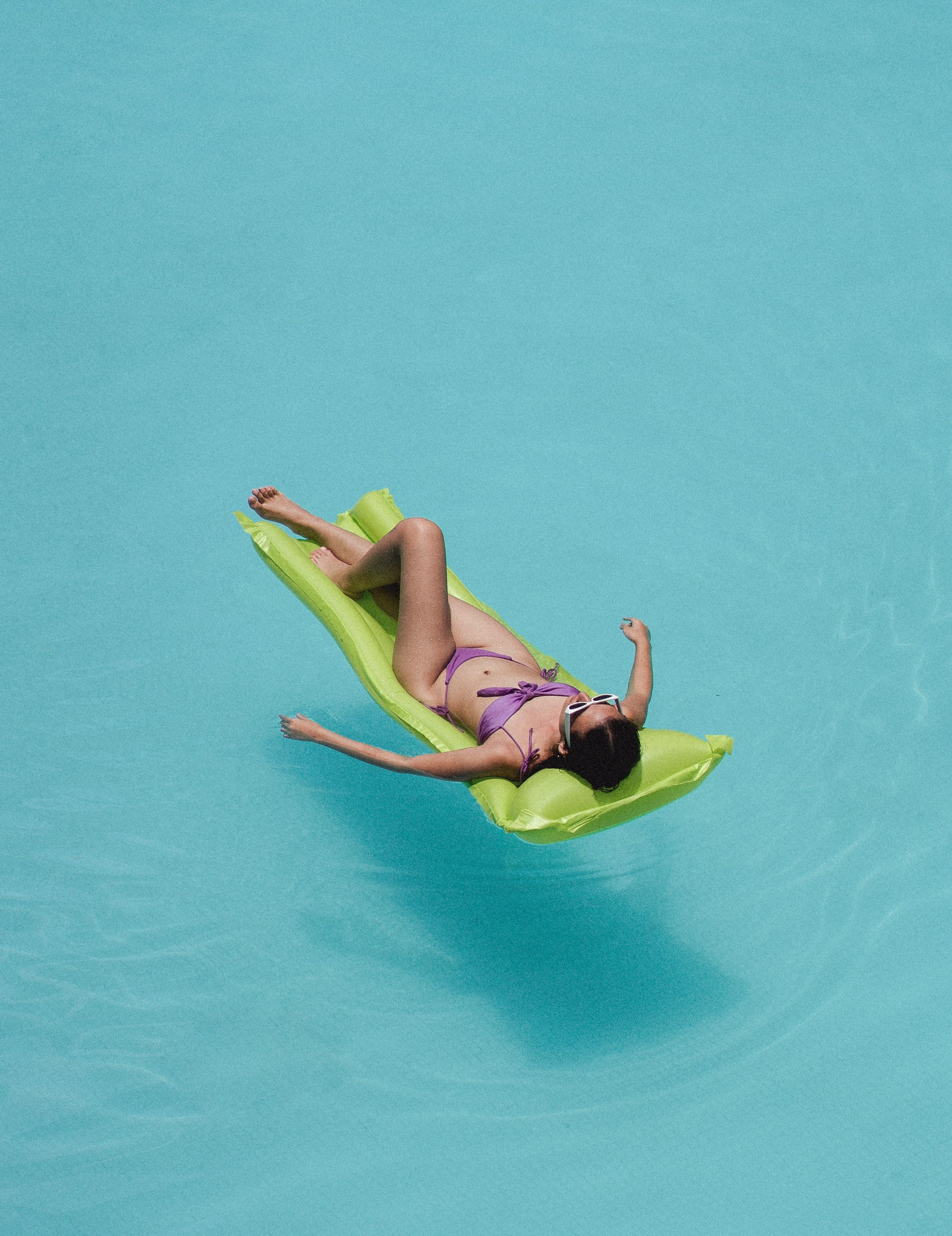 Mulher deitada no colchão de ar em uma piscina