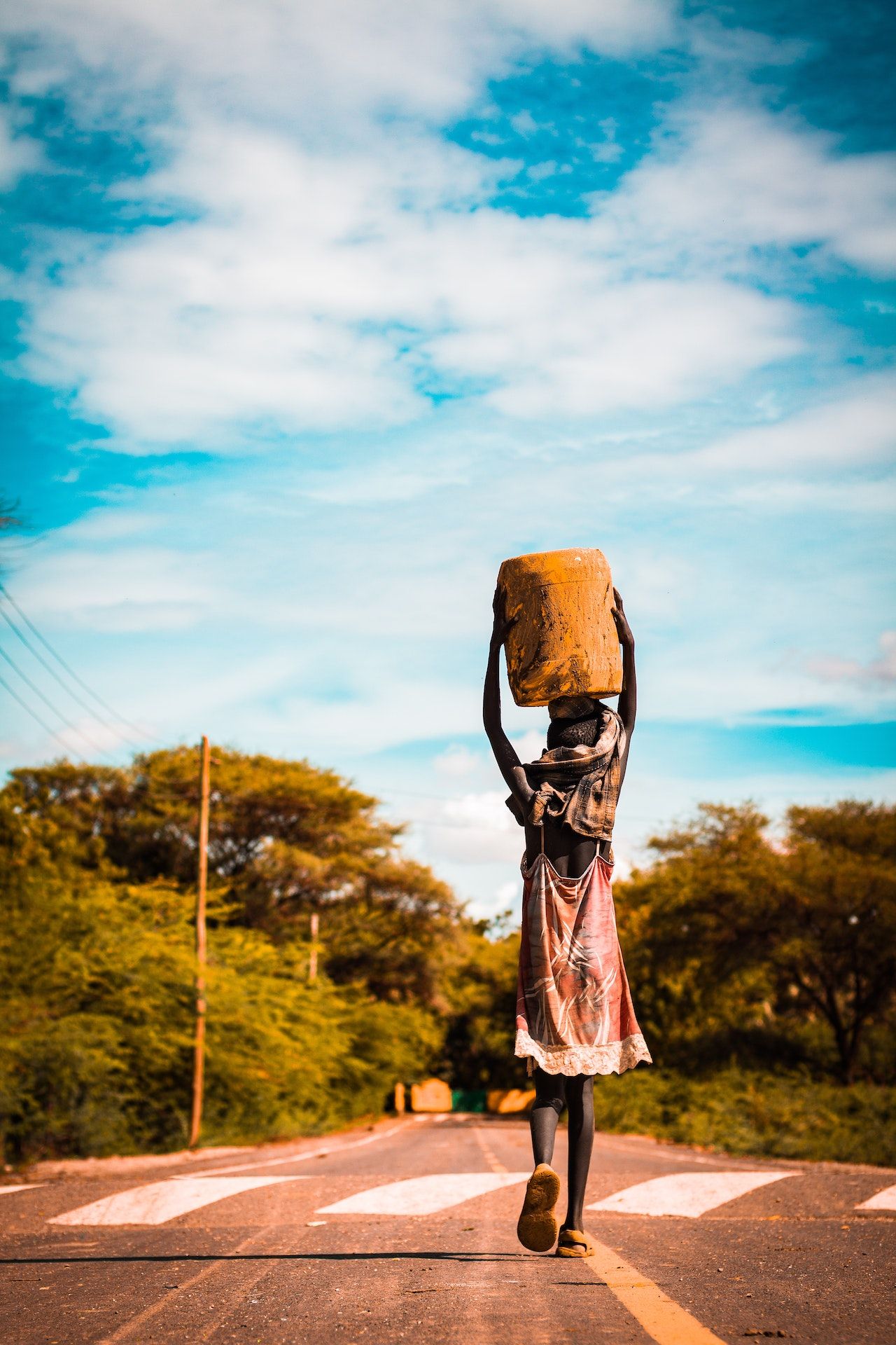 Person carrying container on the head on road