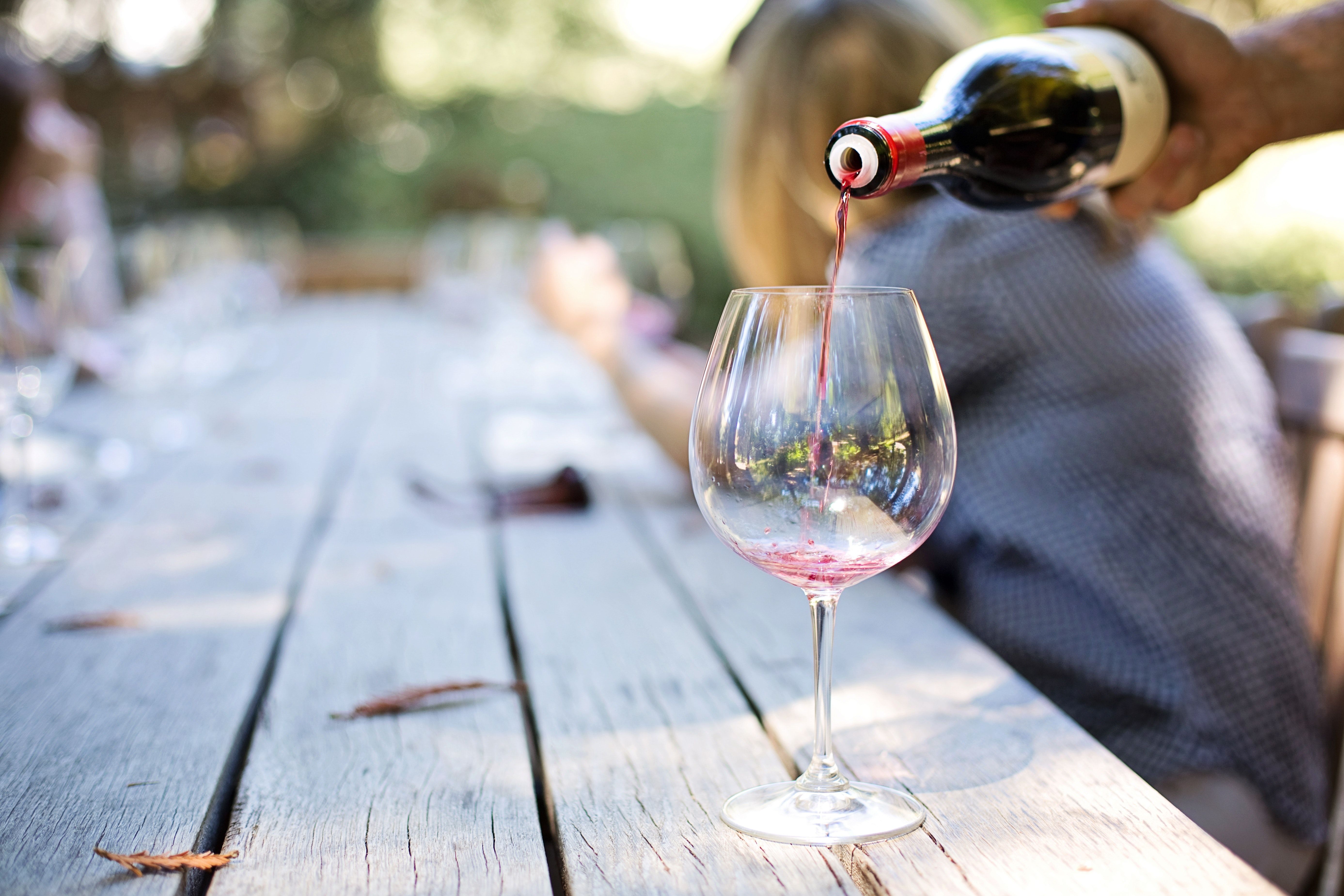 Pouring red wine into wine glass outside at a vineyard