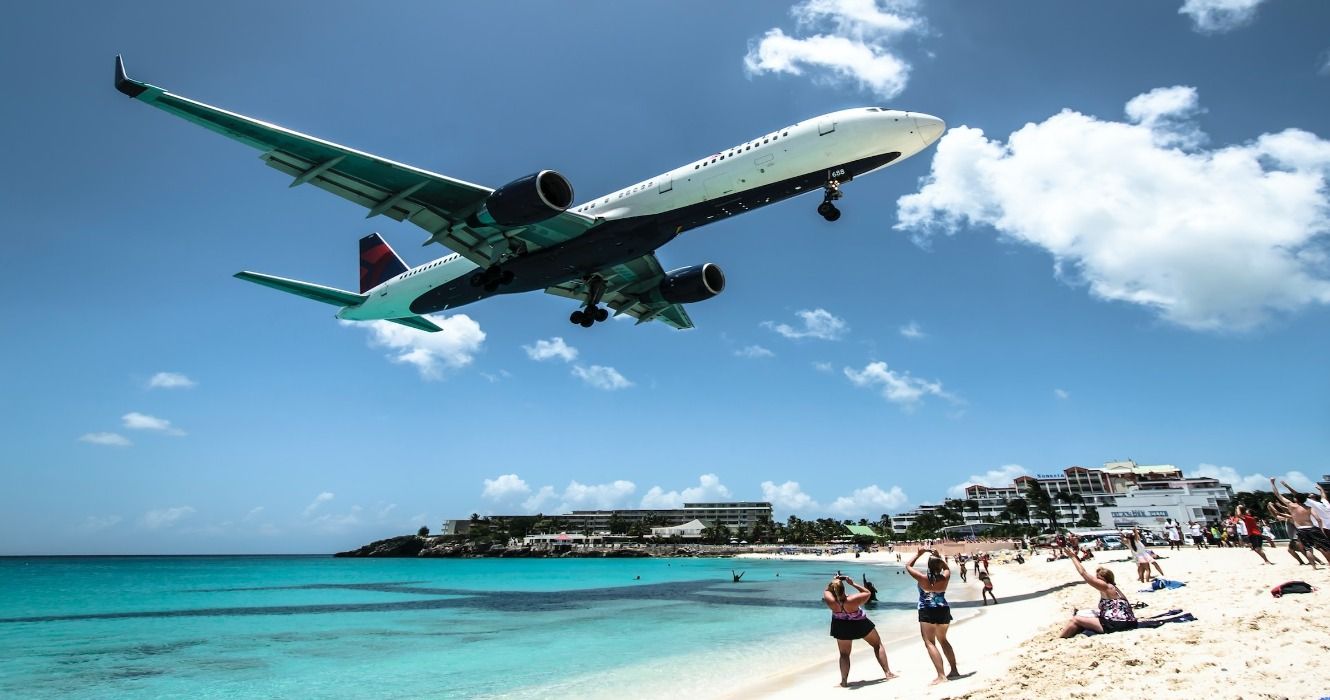 A commercial airplane flying over people on Maho Beach in St Martin