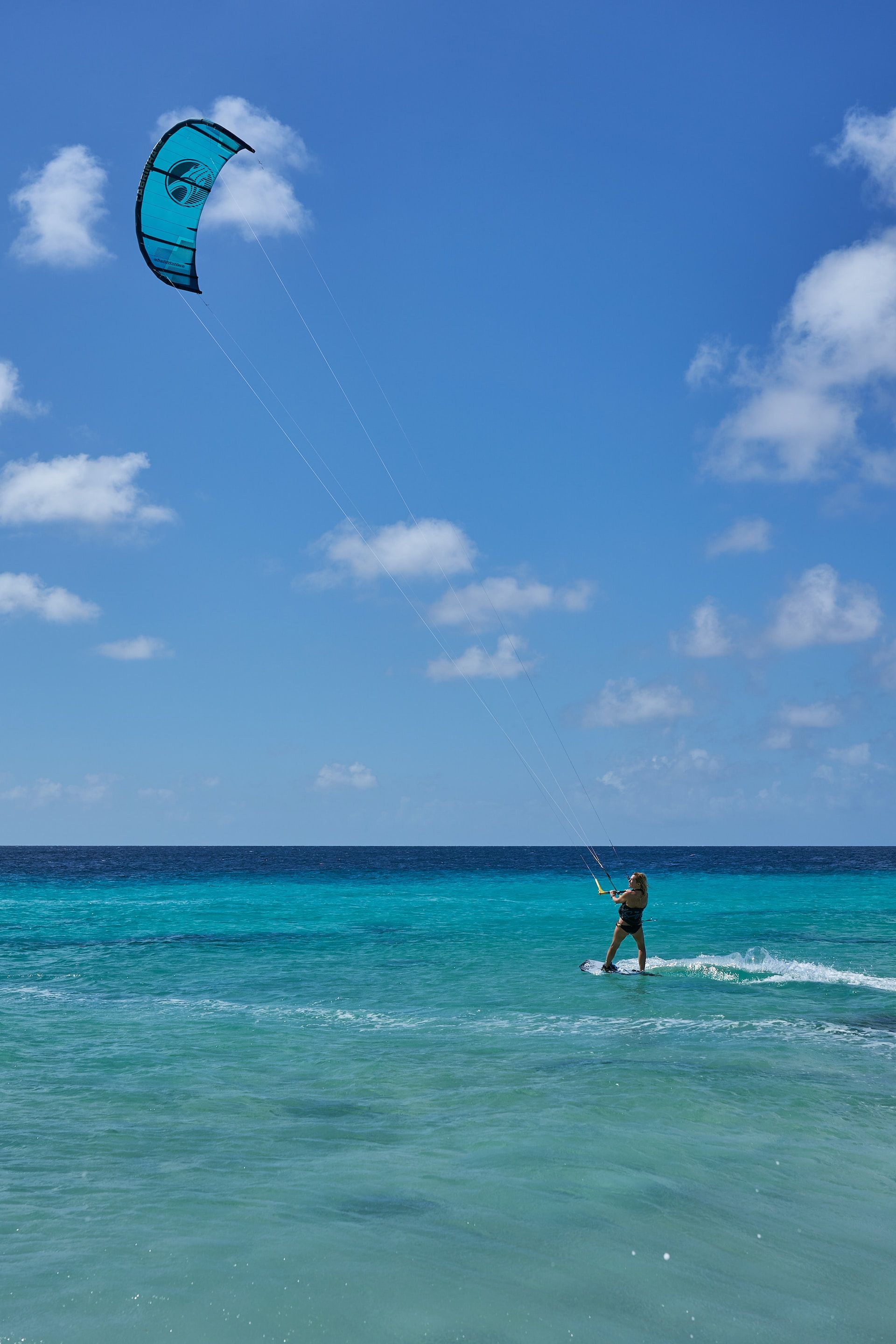 a thrill-seeker kitesurfing with blue kite 