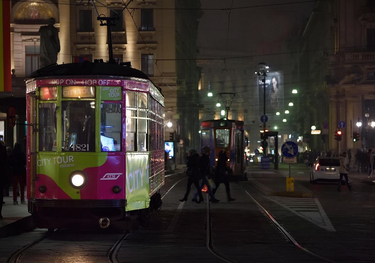 A purple and green tram in Milan at night.