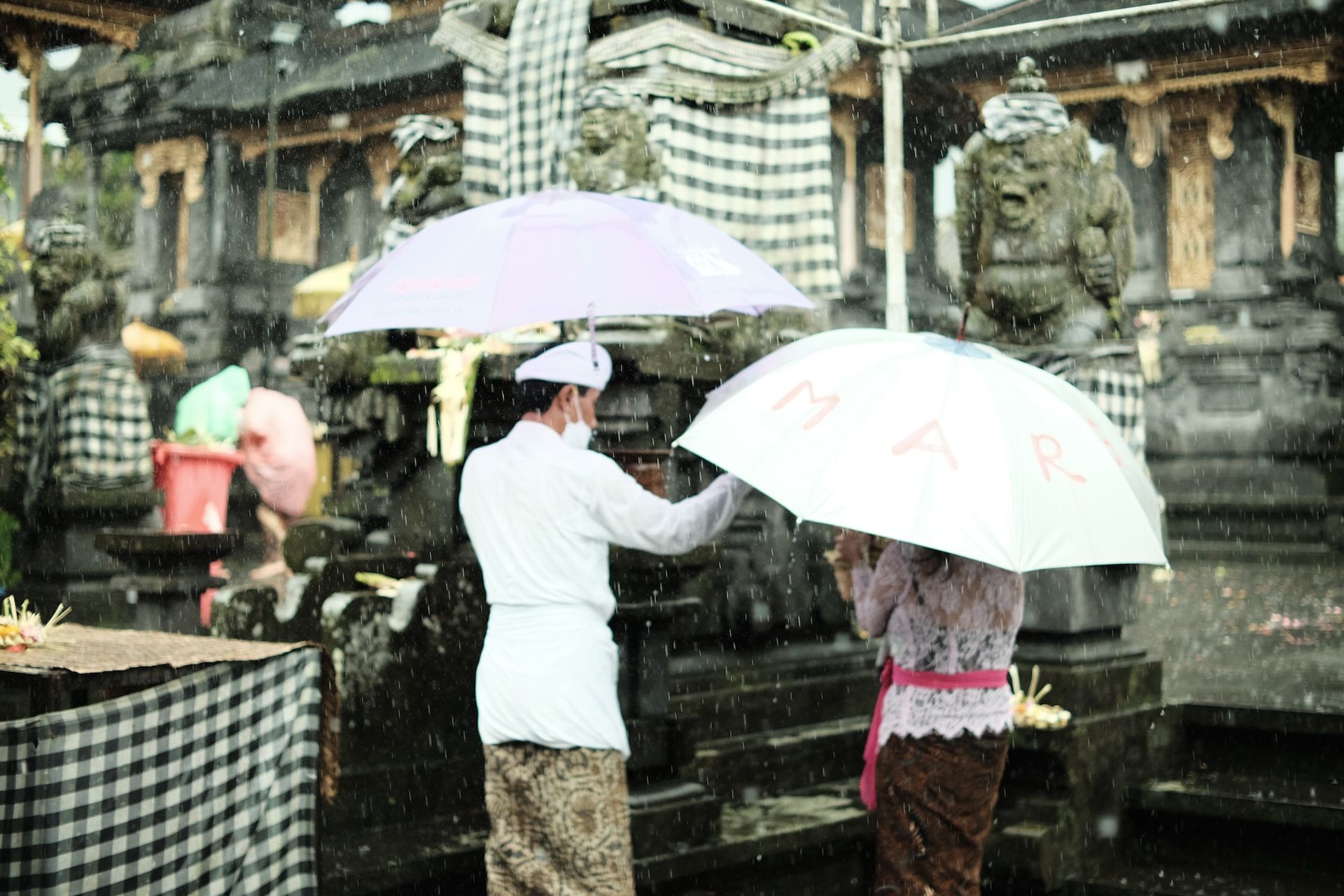 People standing with umbrellas in Bali rain