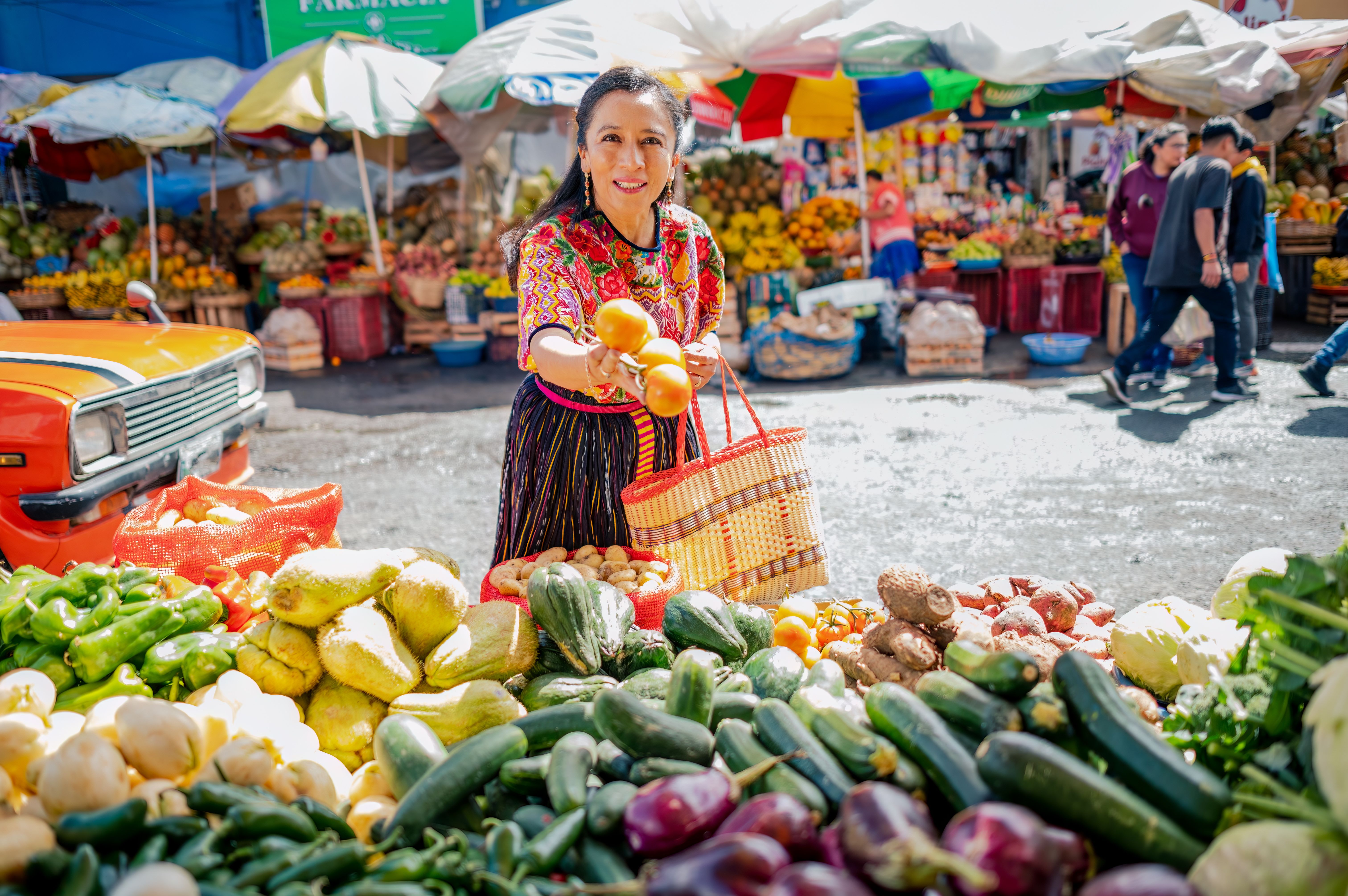 A smiling woman holding fruit at the Mercado Central in Guatemala City