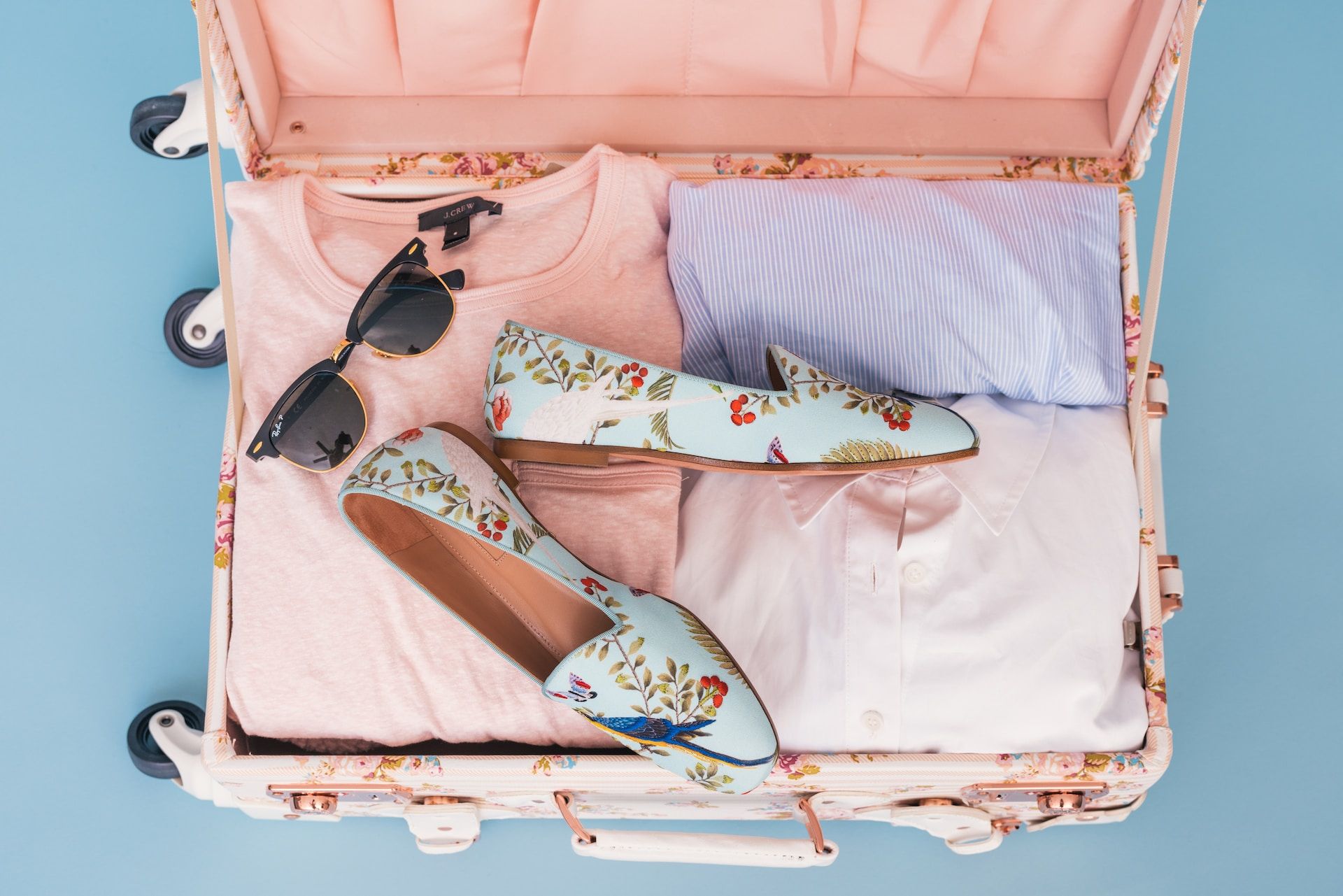 Shades, shoes and clothing in pink suitcase 