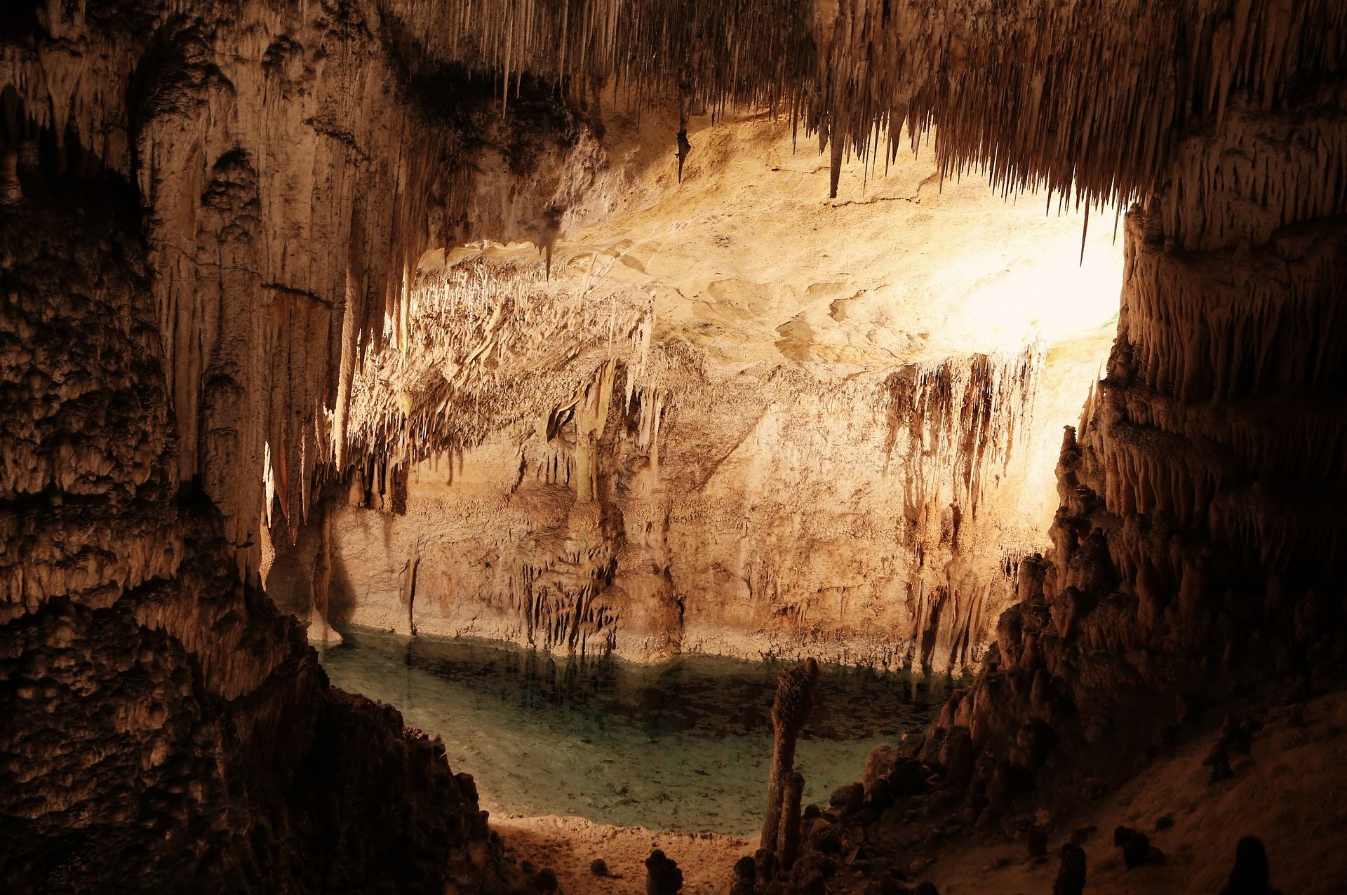 body of water and stalactites in a cavern