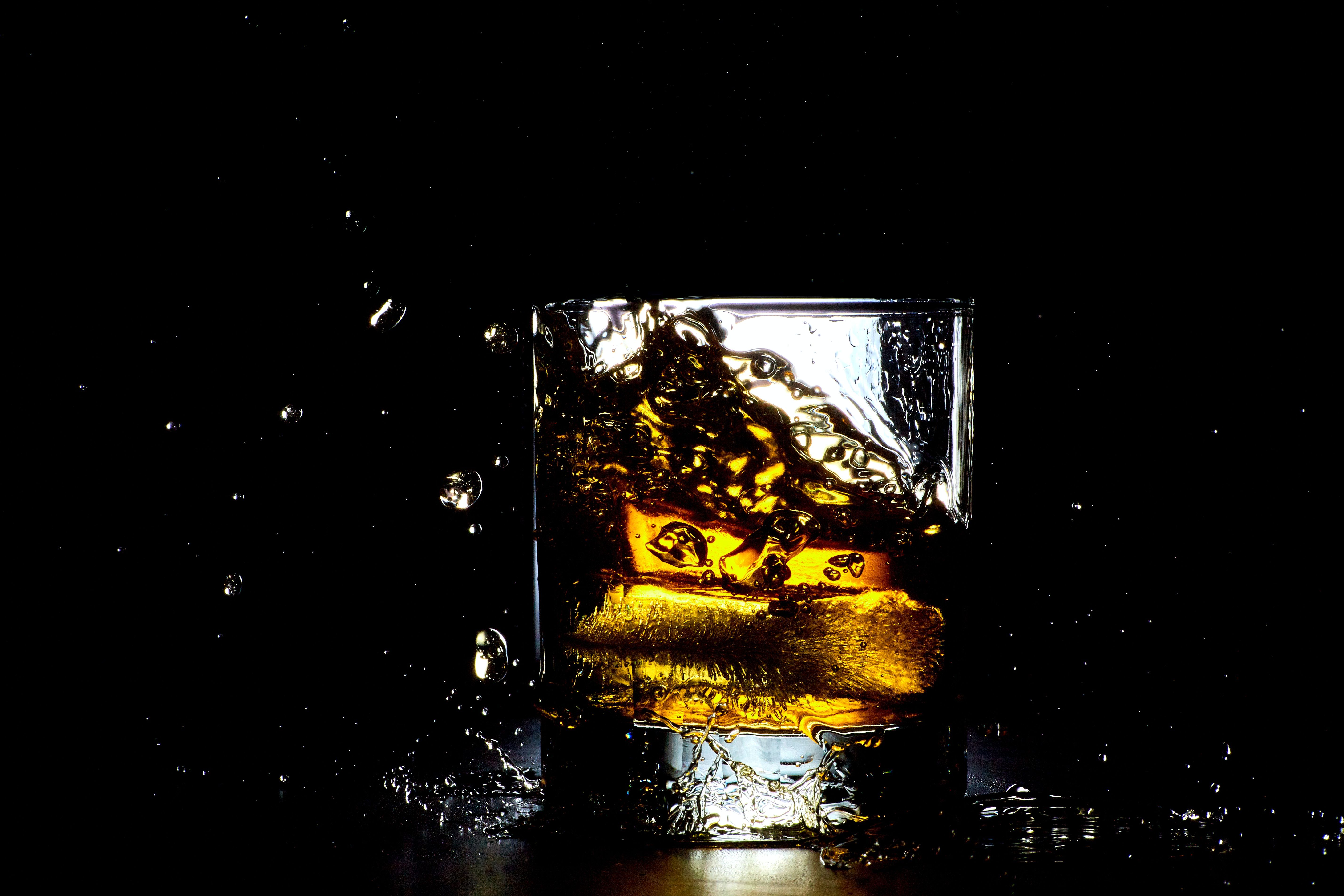 Ice splashing while falling into a glass of whiskey