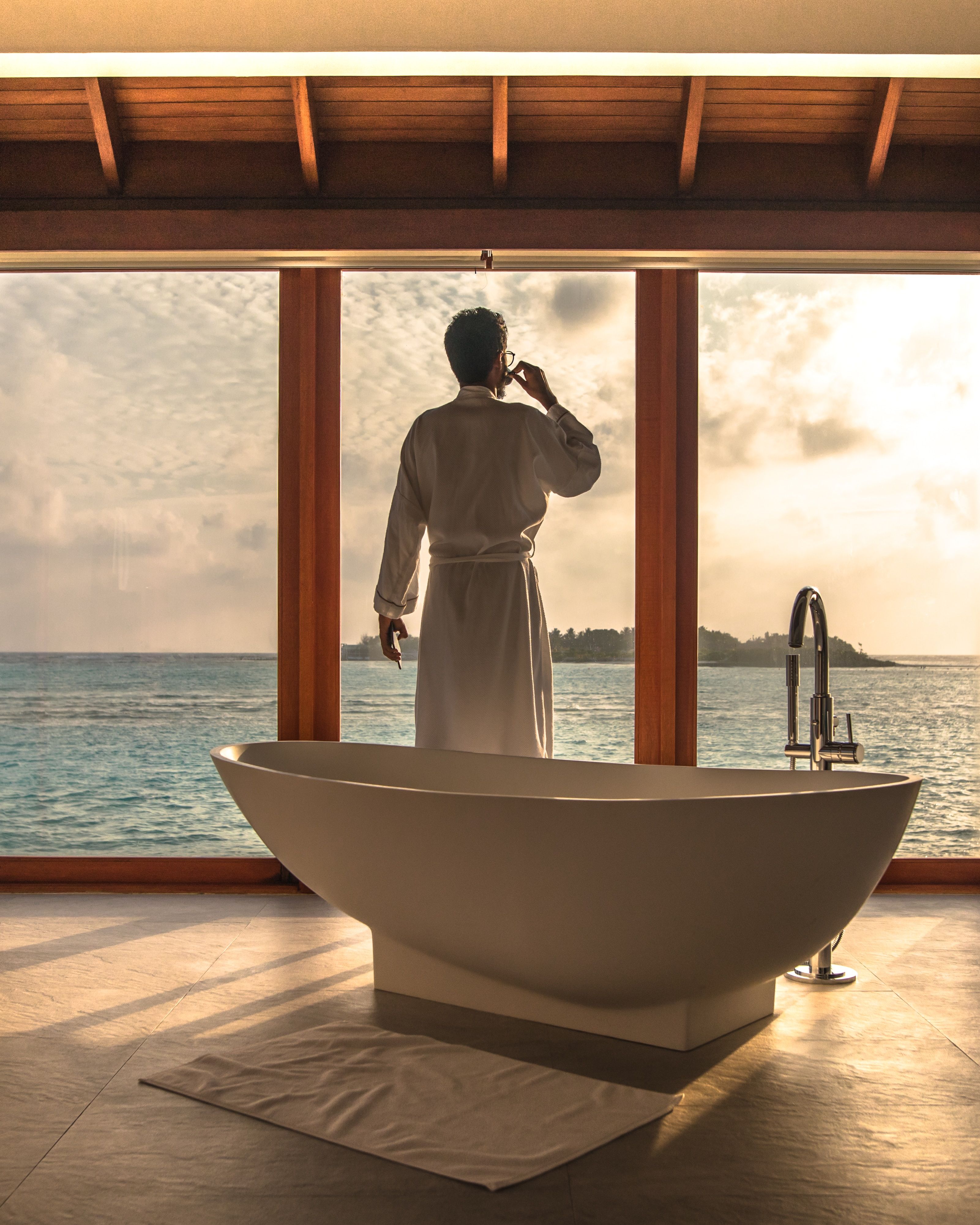 Man in bathrobe looking out into the ocean in the Maldives