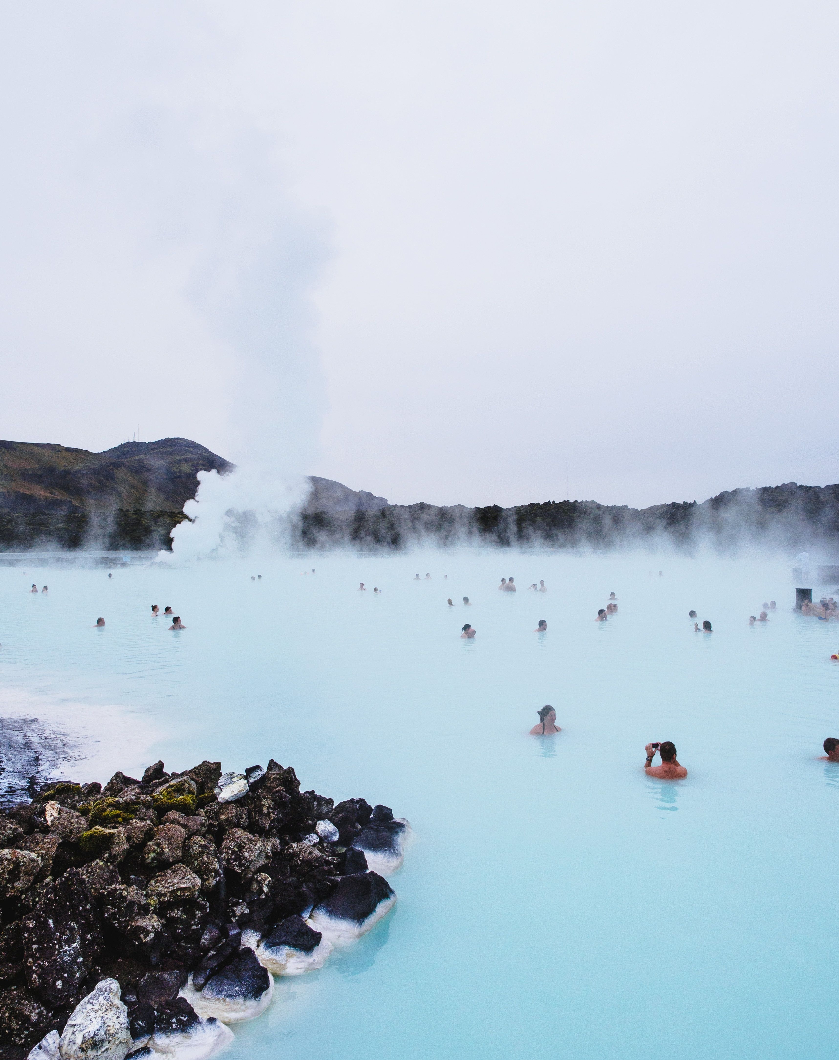 People swimming in the blue waters of the hot spring 