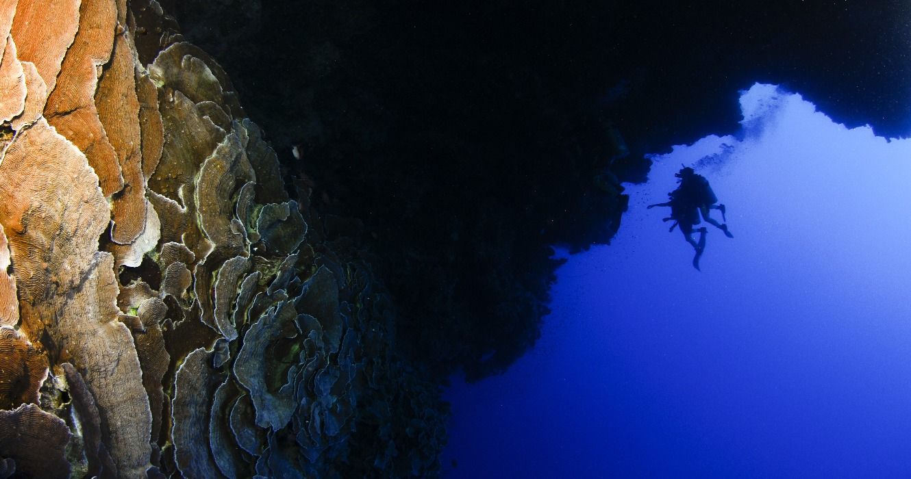 A scuba diver diving into a blue hole