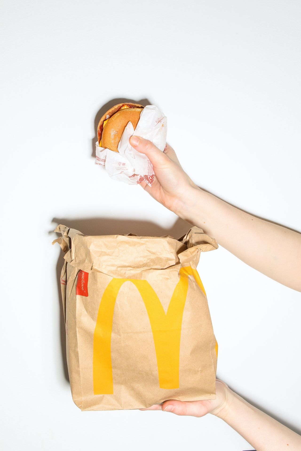 Hand holding a burger over a McDonald's bag