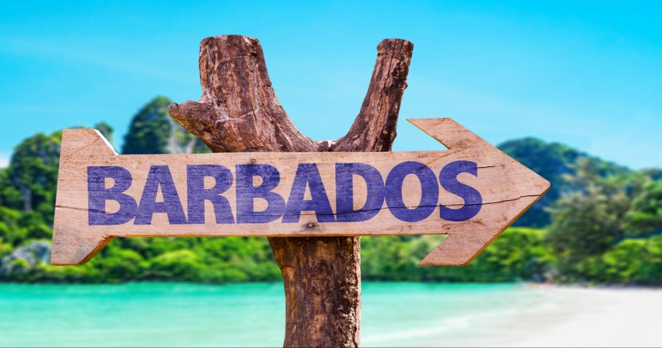 Barbados wooden sign with a beach and mountainous landscape in the background