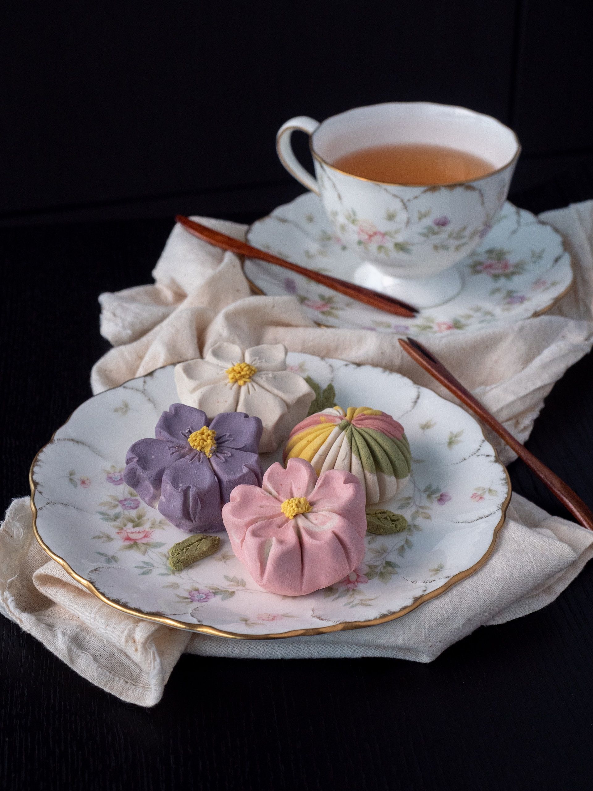 A plate of wagashi next to a cup of tea