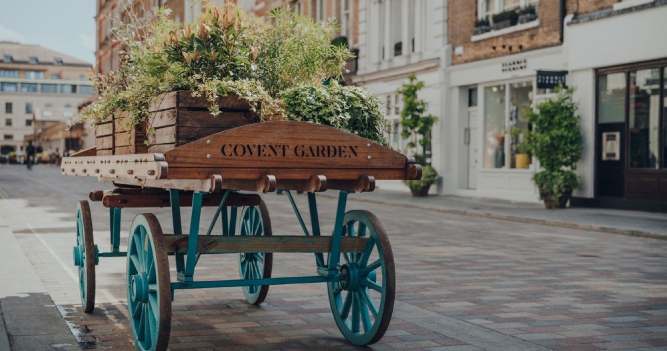'Covent Garden area name sign on a wooden cart with flowers on a street in Covent Garden, London, UK