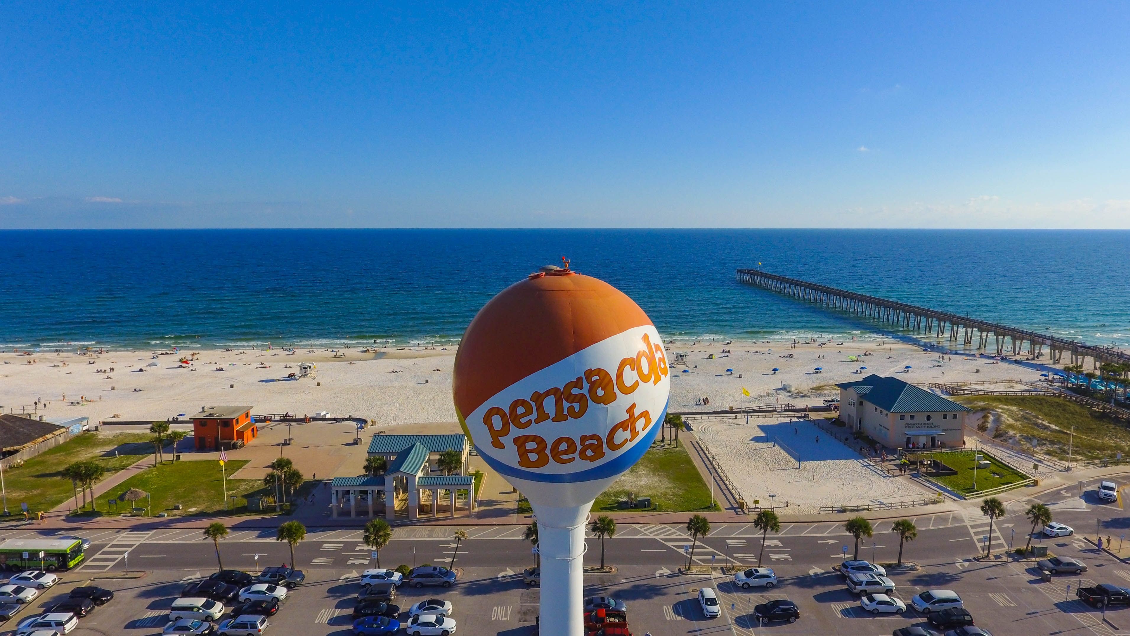 Pensacola Beach water tower, parking lot, beach, and pier at mid-day