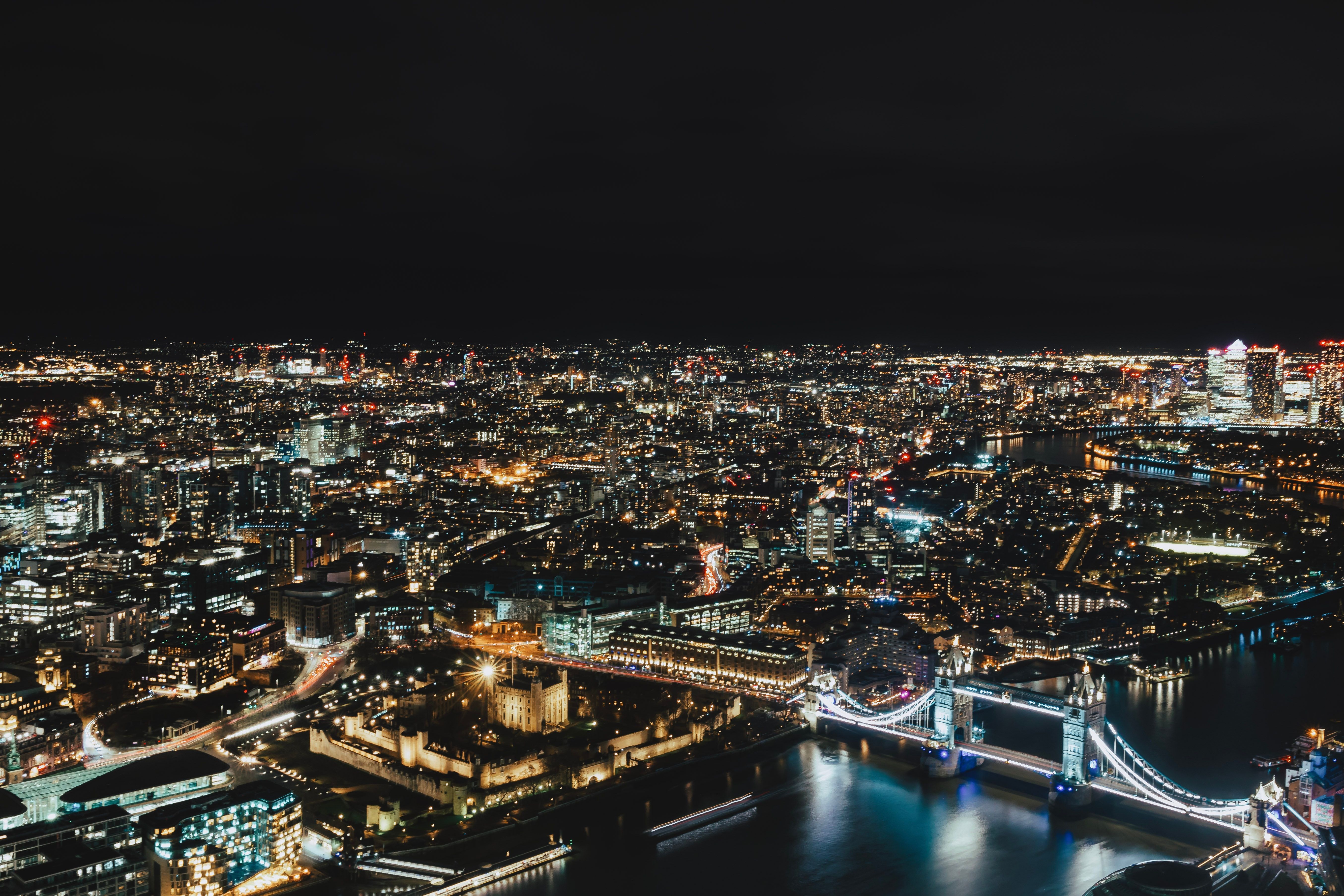 An aerial view of London at night with famous landmarks like the London Bridge, UK