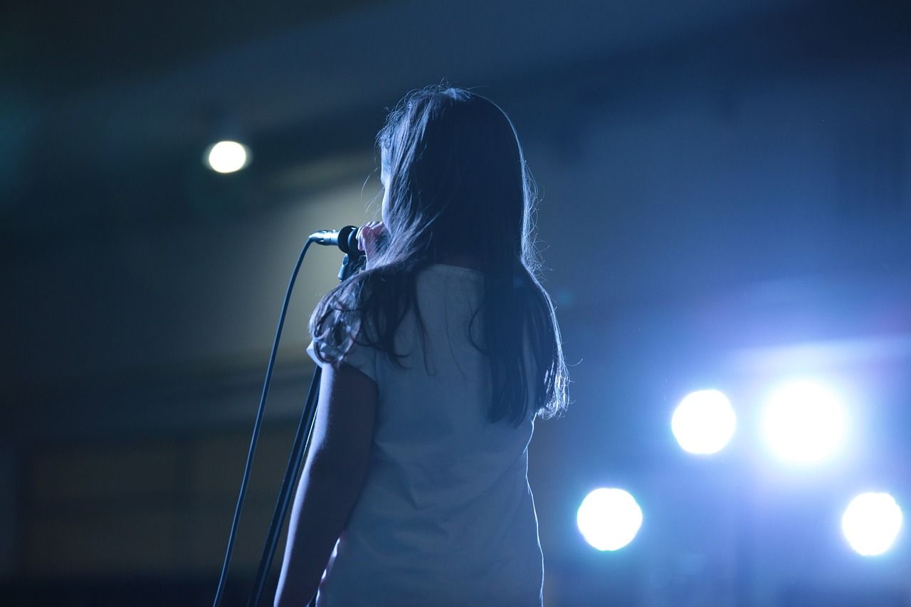 Young girl performing on stage amid bright lights